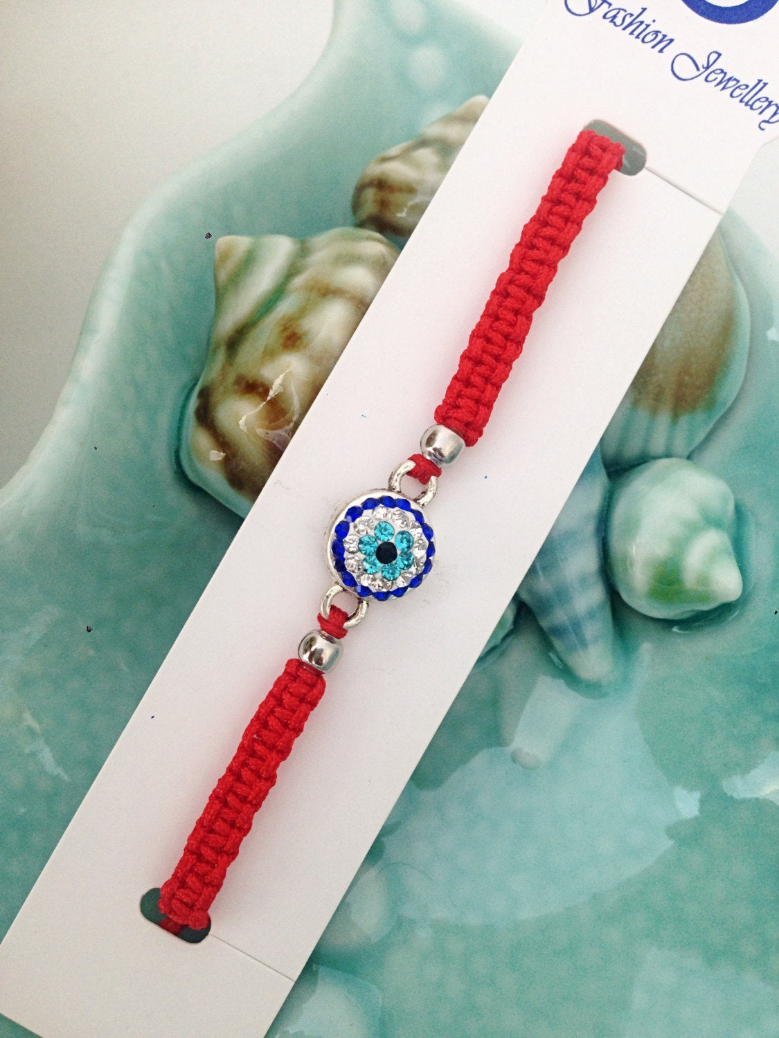 Handmade red macramé evil eye bracelet with adjustable design, featuring a protective evil eye charm.