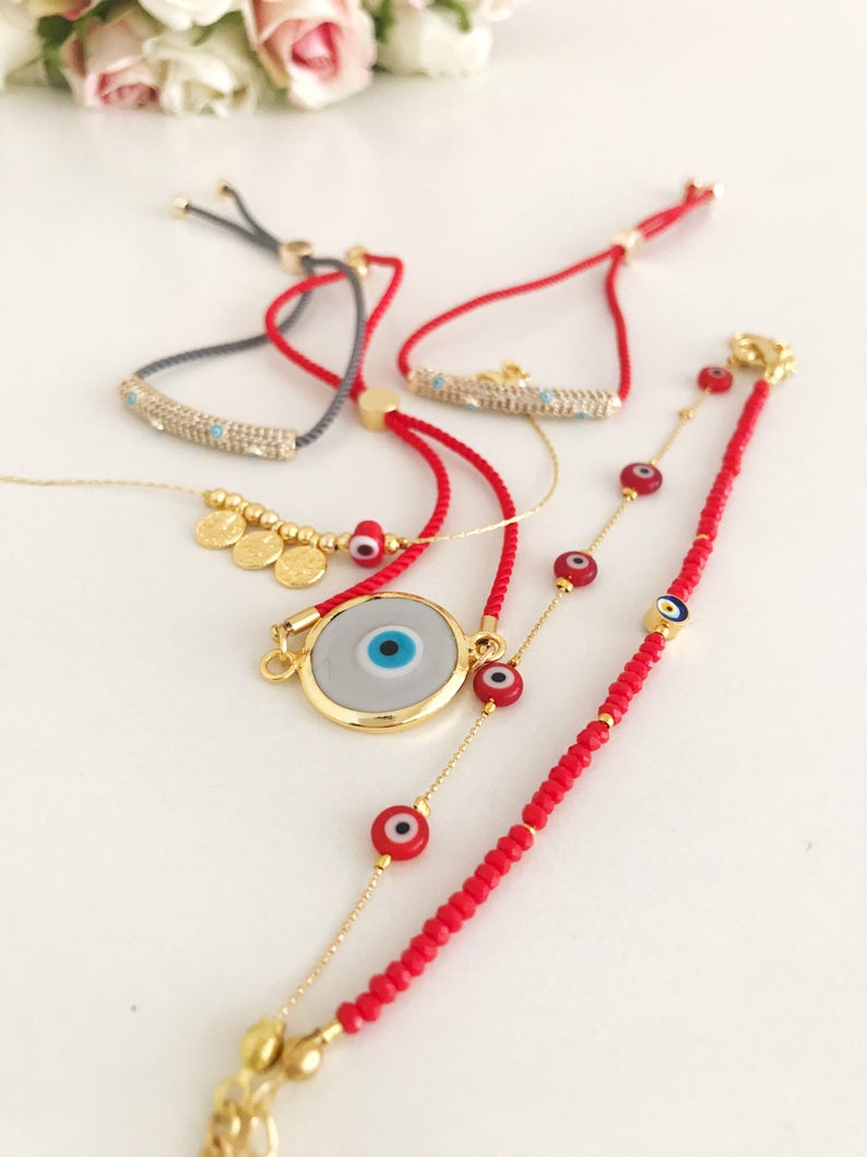 A beautiful collection of Red Evil Eye Jewelry including a bracelet and necklace made with red Murano glass and gold accents, symbolizing protection and good luck.