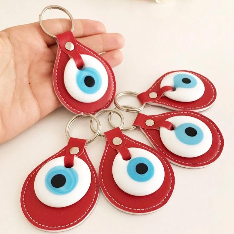 A vibrant red leather keychain featuring a glass evil eye, symbolizing protection and good luck, perfect for keys or bags.