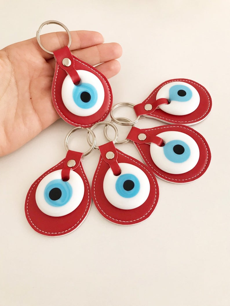 A vibrant red leather keychain featuring a glass evil eye, symbolizing protection and good luck, perfect for keys or bags.