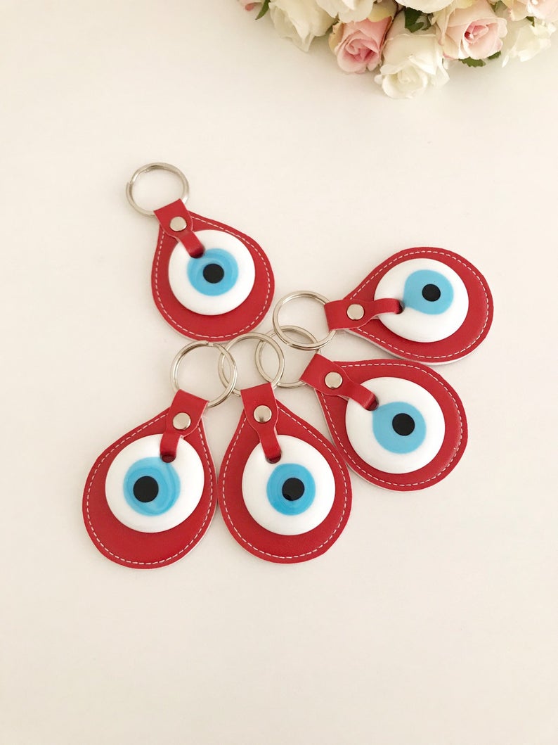 A vibrant red leather keychain featuring a glass evil eye, symbolizing protection and good luck, perfect for keys or bags.