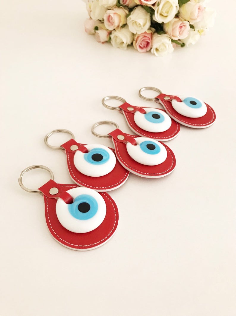 A vibrant red leather keychain featuring a glass evil eye, symbolizing protection and good luck, perfect for keys or bags.