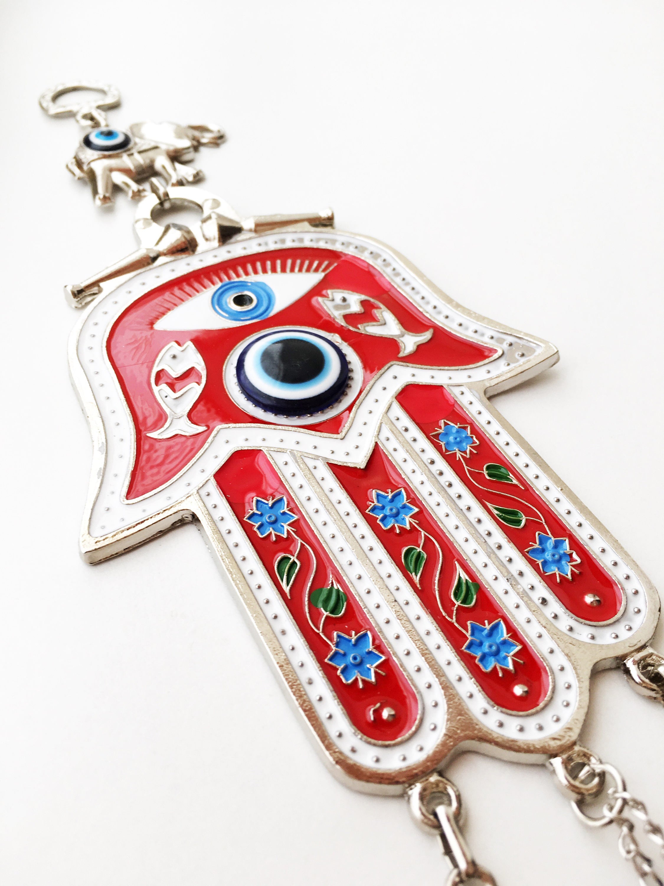 A vibrant red Hamsa evil eye wall hanging featuring a mosaic metal hand and a large evil eye bead, symbolizing protection and good luck.