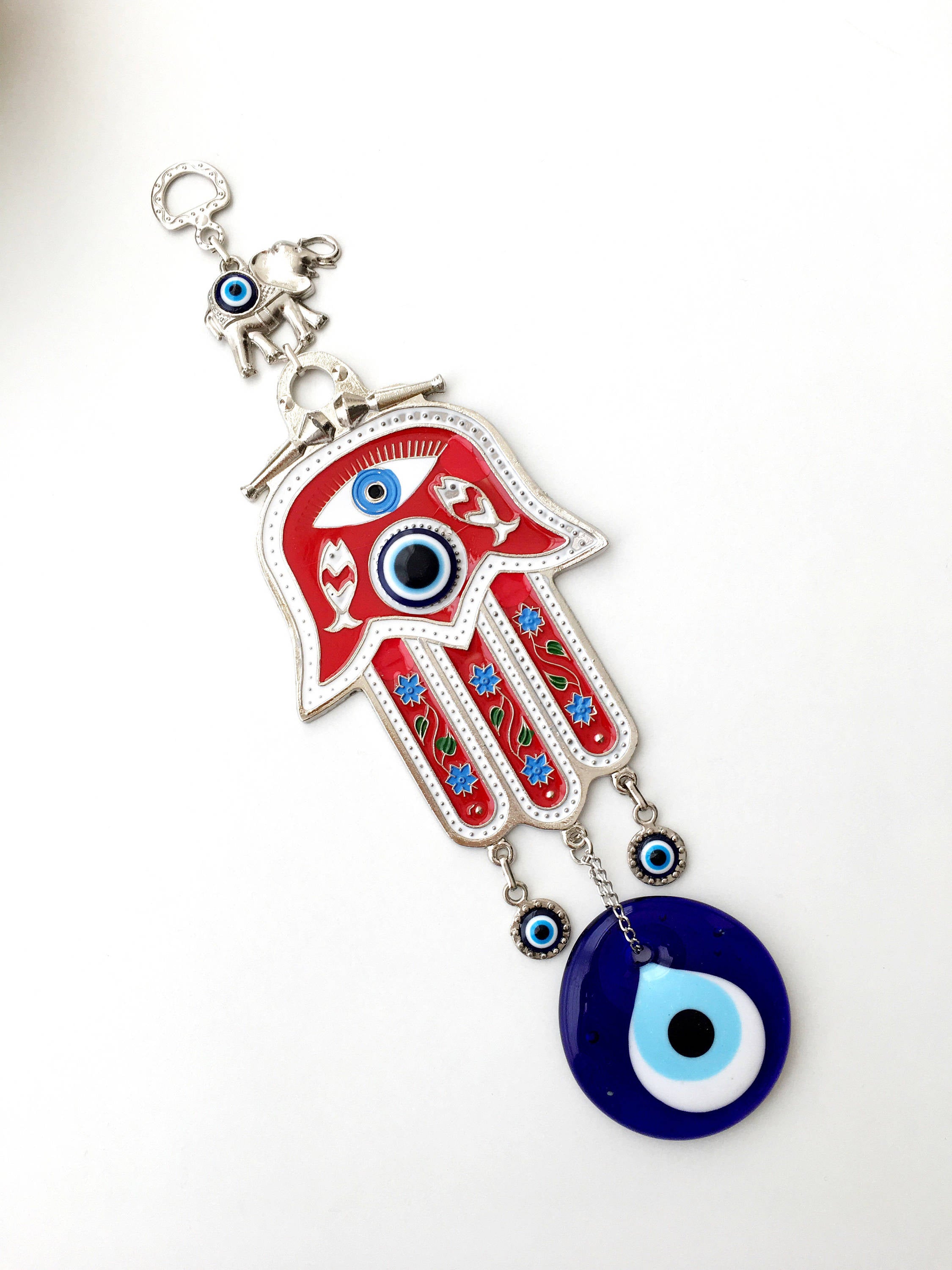 A vibrant red Hamsa evil eye wall hanging featuring a mosaic metal hand and a large evil eye bead, symbolizing protection and good luck.