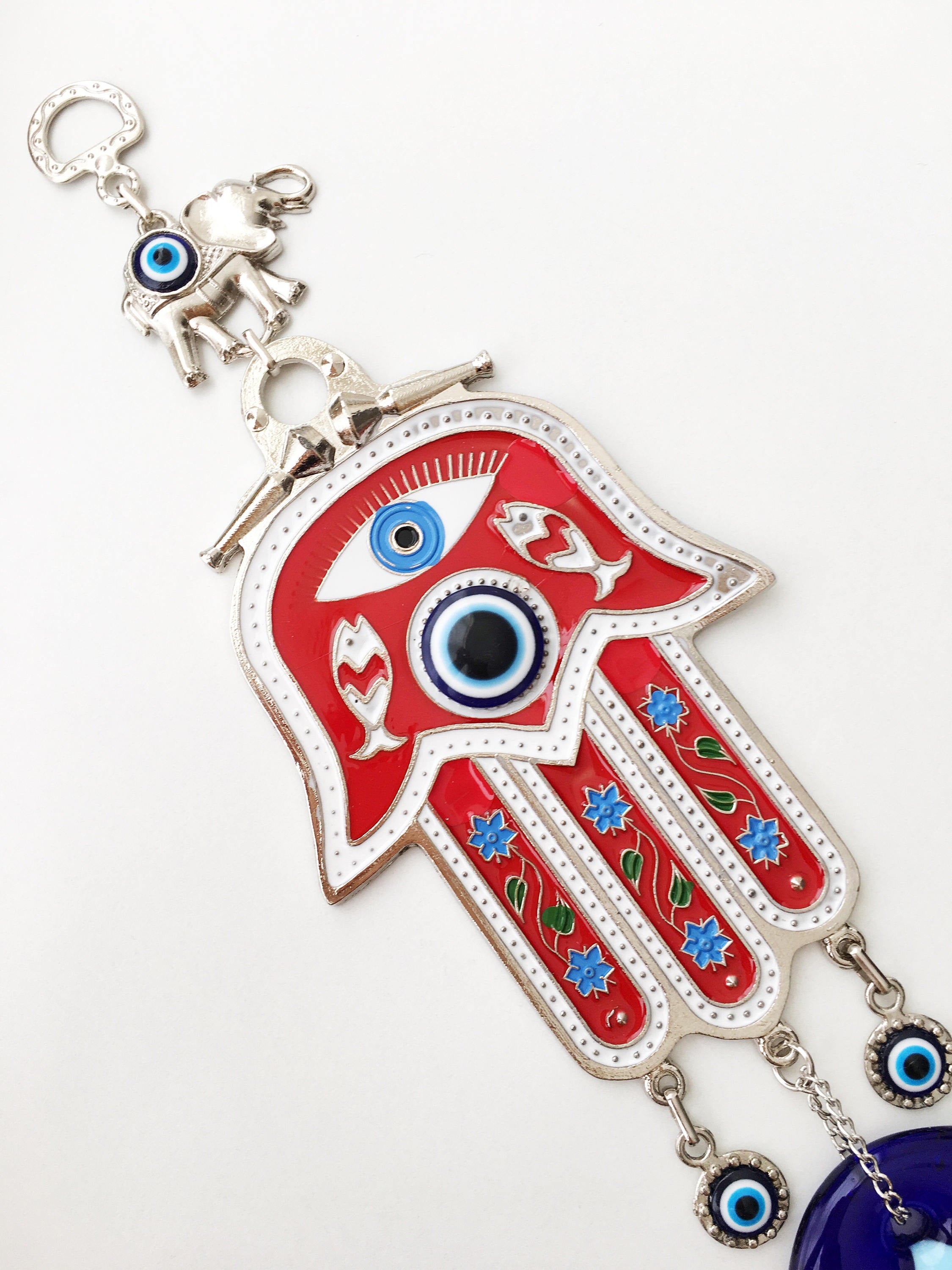 A vibrant red Hamsa evil eye wall hanging featuring a mosaic metal hand and a large evil eye bead, symbolizing protection and good luck.