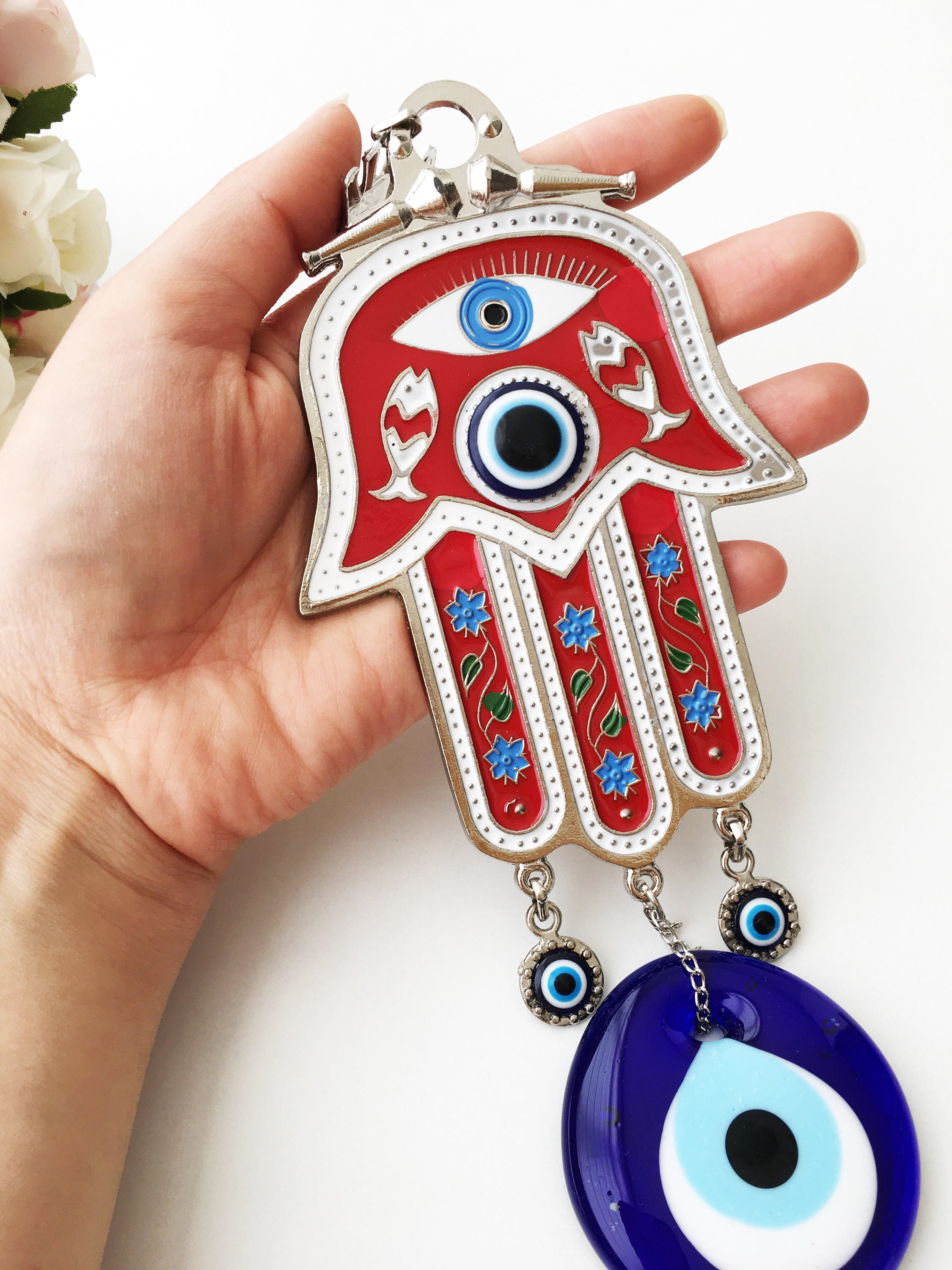 A vibrant red Hamsa evil eye wall hanging featuring a mosaic metal hand and a large evil eye bead, symbolizing protection and good luck.