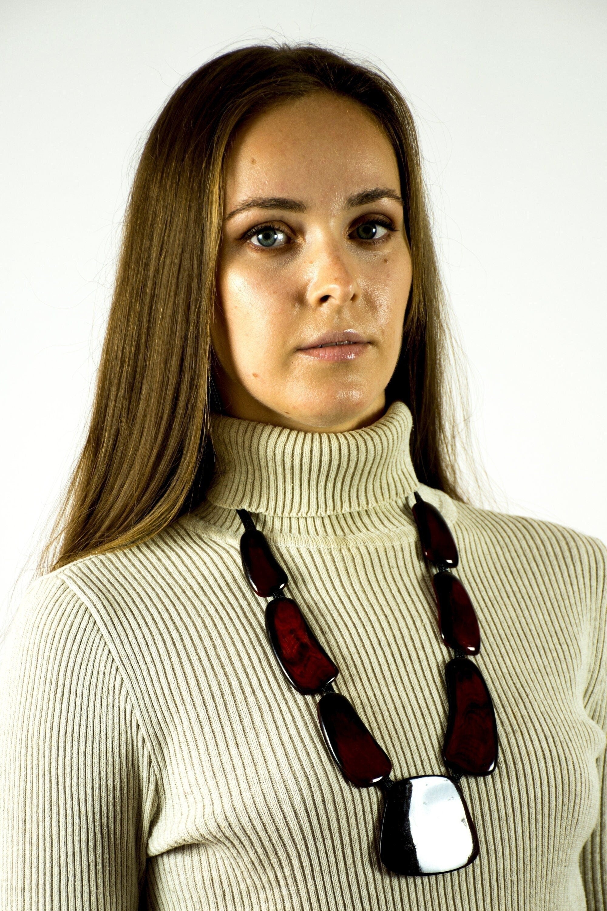 A handmade red necklace for women, crafted from cow horn and connected with a black leather cord, showcasing a unique and stylish design.