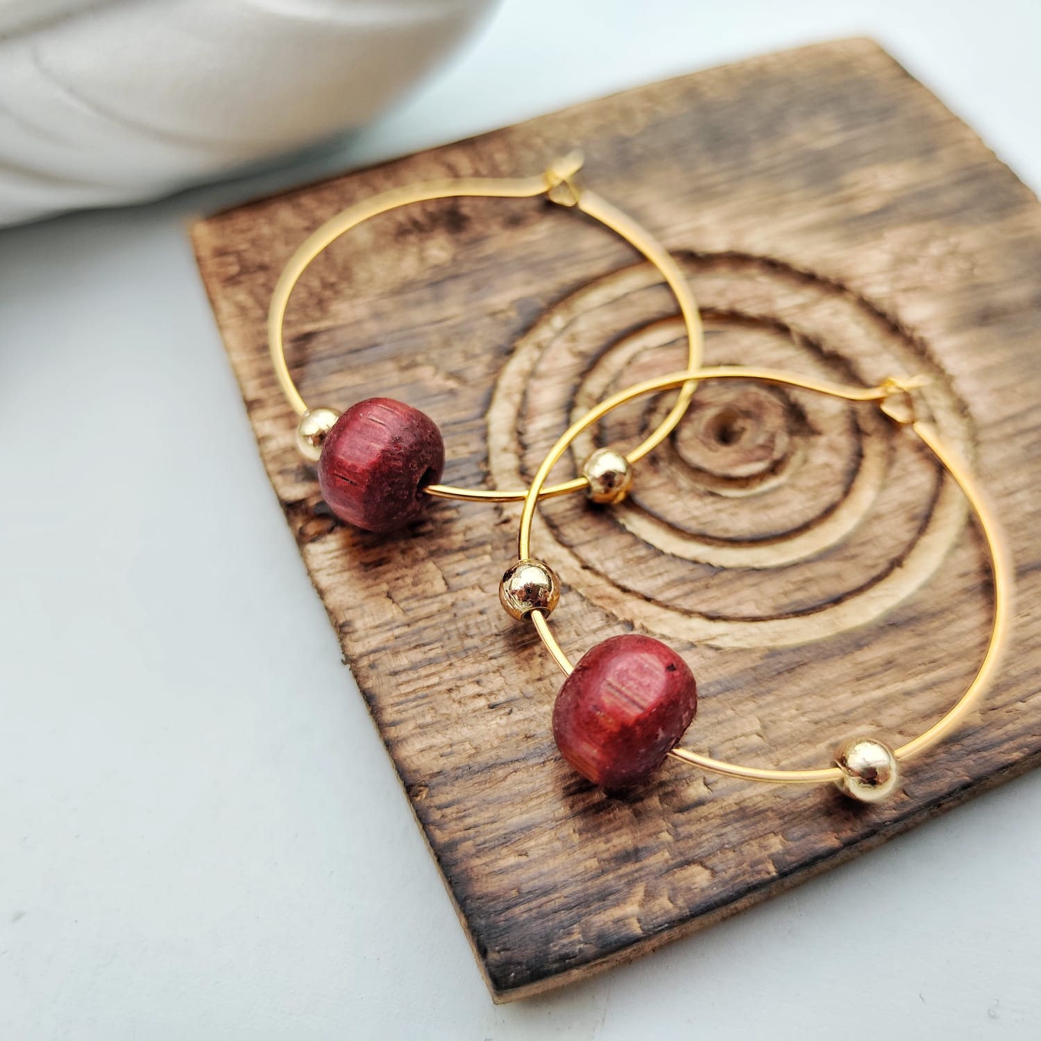 A pair of elegant red sandalwood beaded hoop earrings, showcasing their minimalist design and vibrant color.