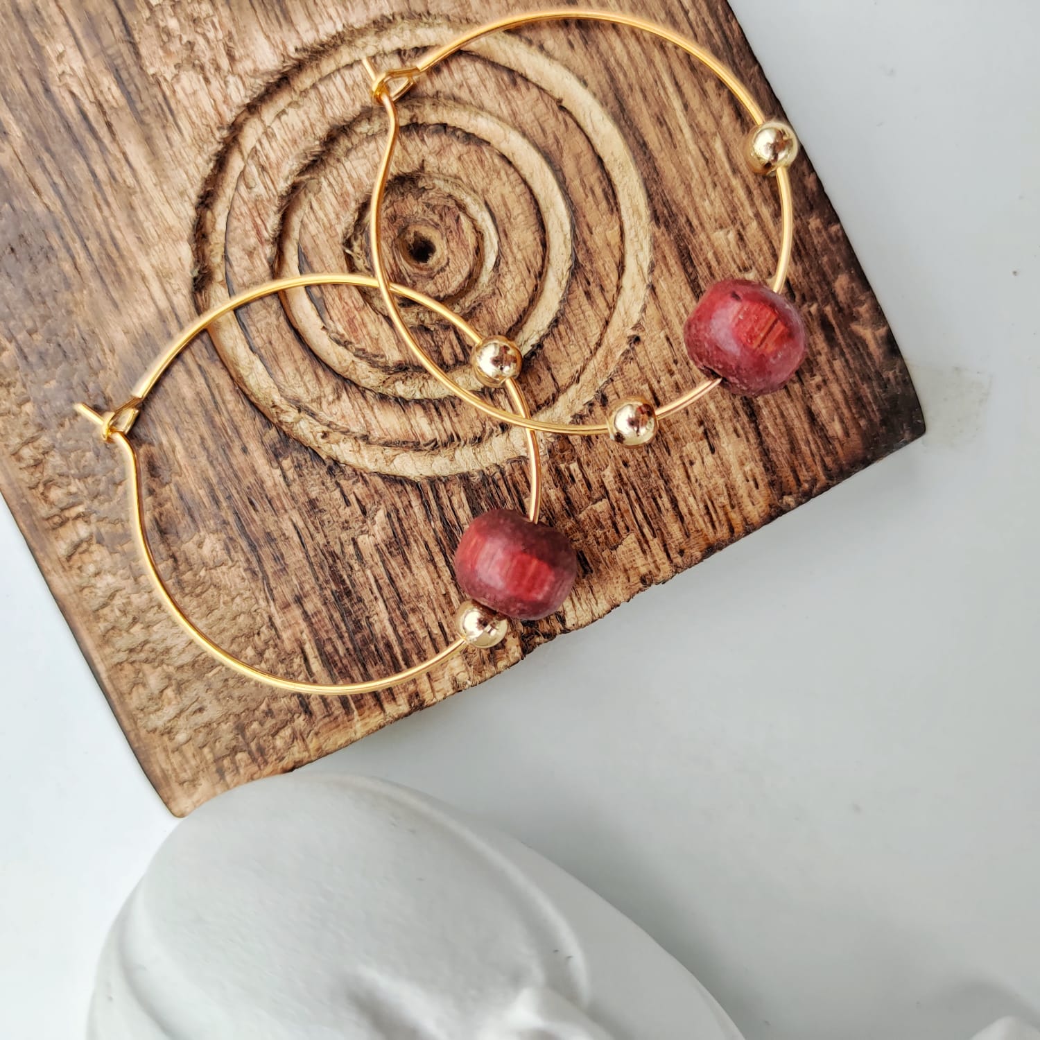 A pair of elegant red sandalwood beaded hoop earrings, showcasing their minimalist design and vibrant color.