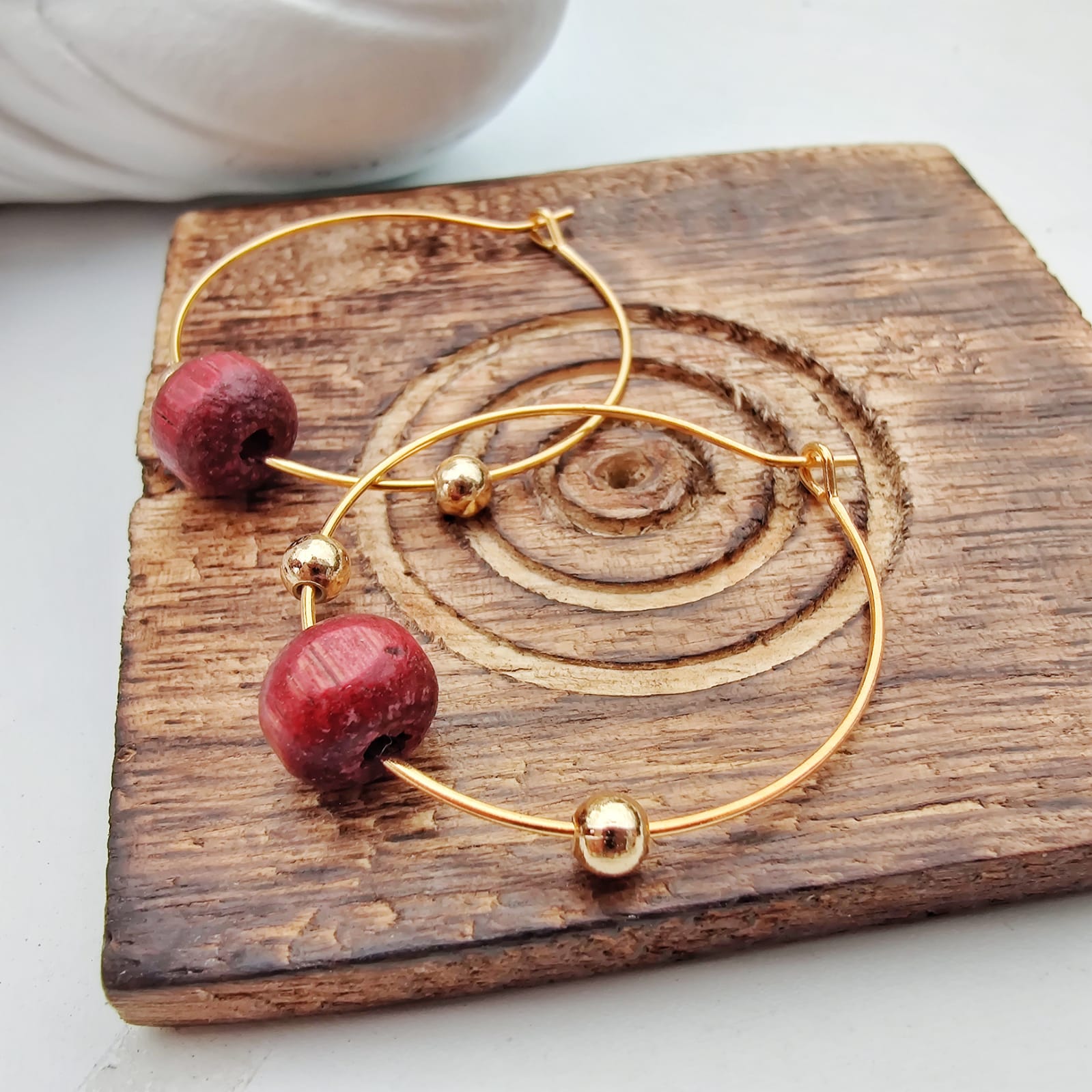 A pair of elegant red sandalwood beaded hoop earrings, showcasing their minimalist design and vibrant color.