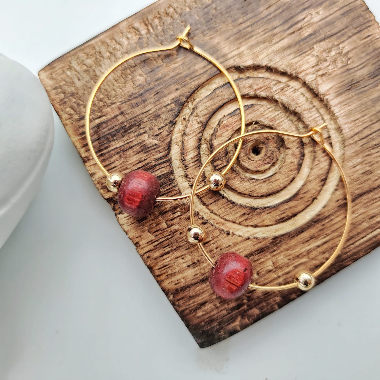 A pair of elegant red sandalwood beaded hoop earrings, showcasing their minimalist design and vibrant color.