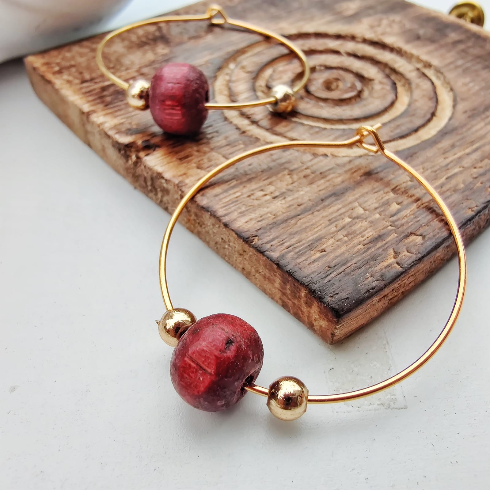 A pair of elegant red sandalwood beaded hoop earrings, showcasing their minimalist design and vibrant color.