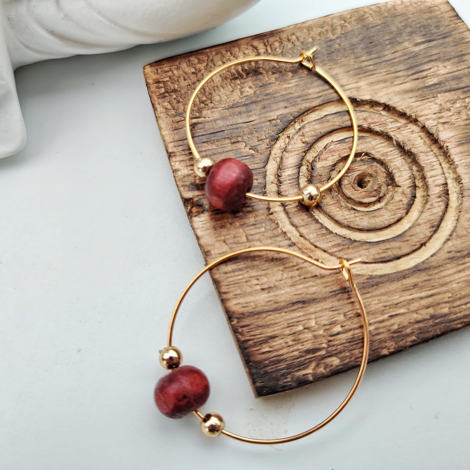 A pair of elegant red sandalwood beaded hoop earrings, showcasing their minimalist design and vibrant color.