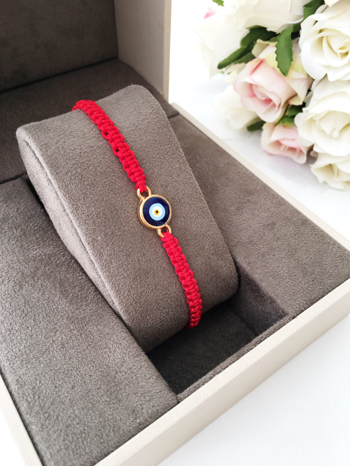 Handmade red string evil eye bracelet featuring a blue charm, adjustable for all wrist sizes.