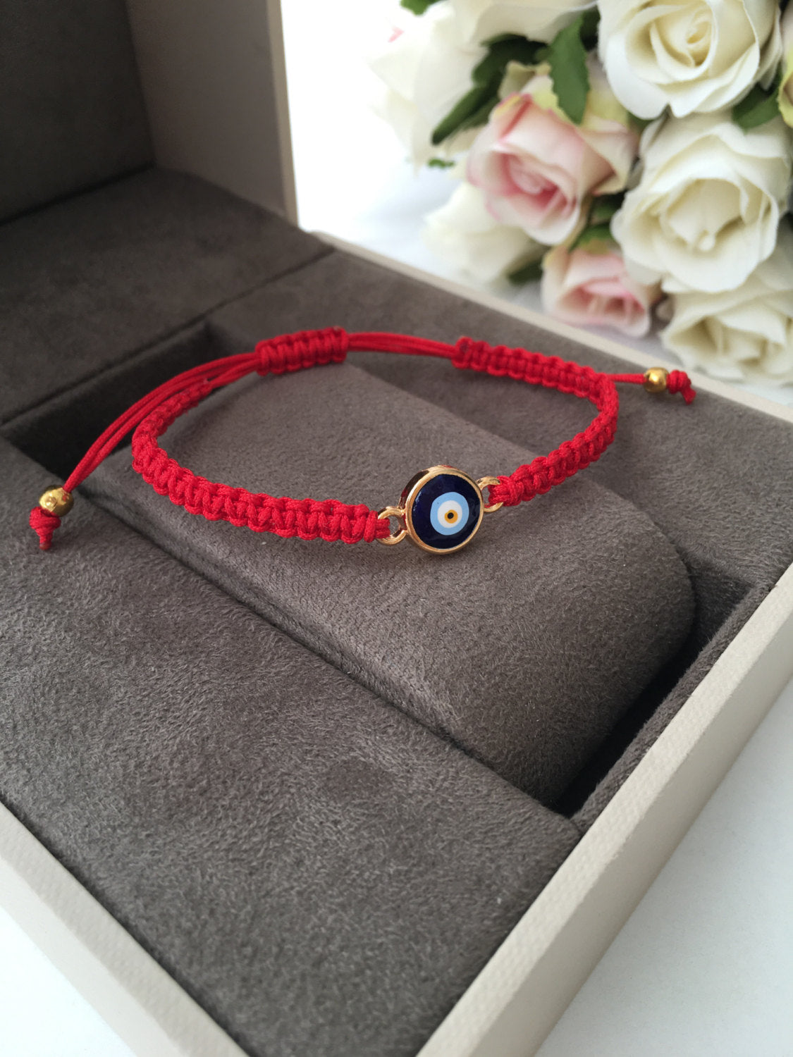 Handmade red string evil eye bracelet featuring a blue charm, adjustable for all wrist sizes.