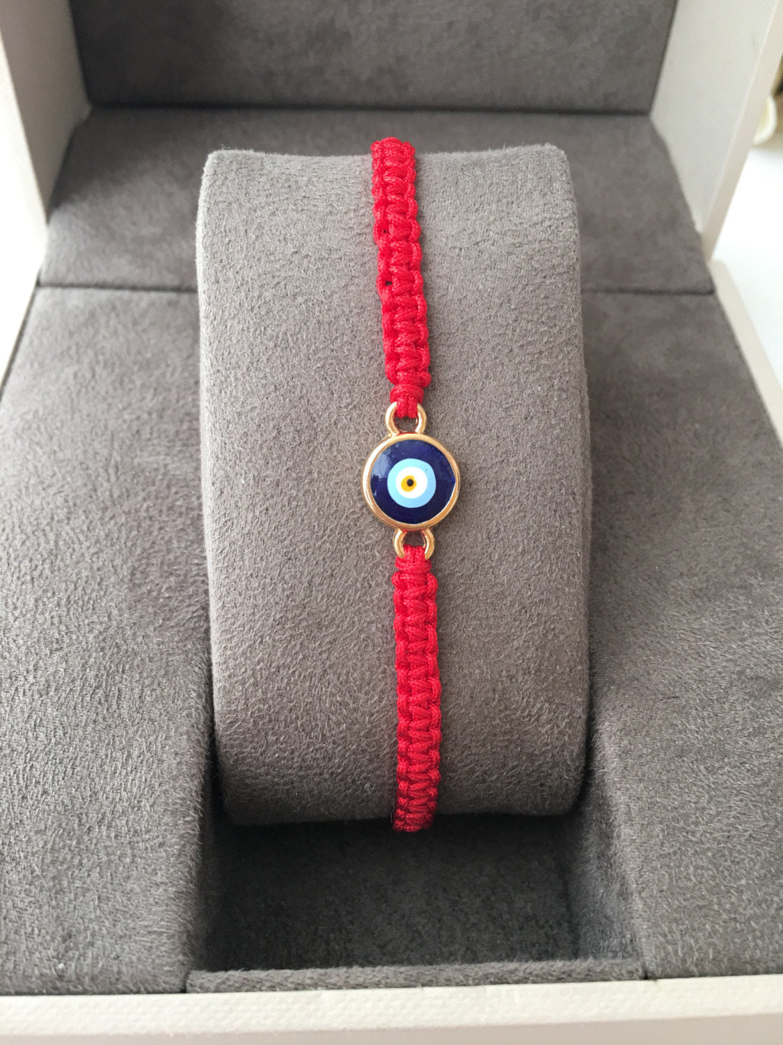 Handmade red string evil eye bracelet featuring a blue charm, adjustable for all wrist sizes.