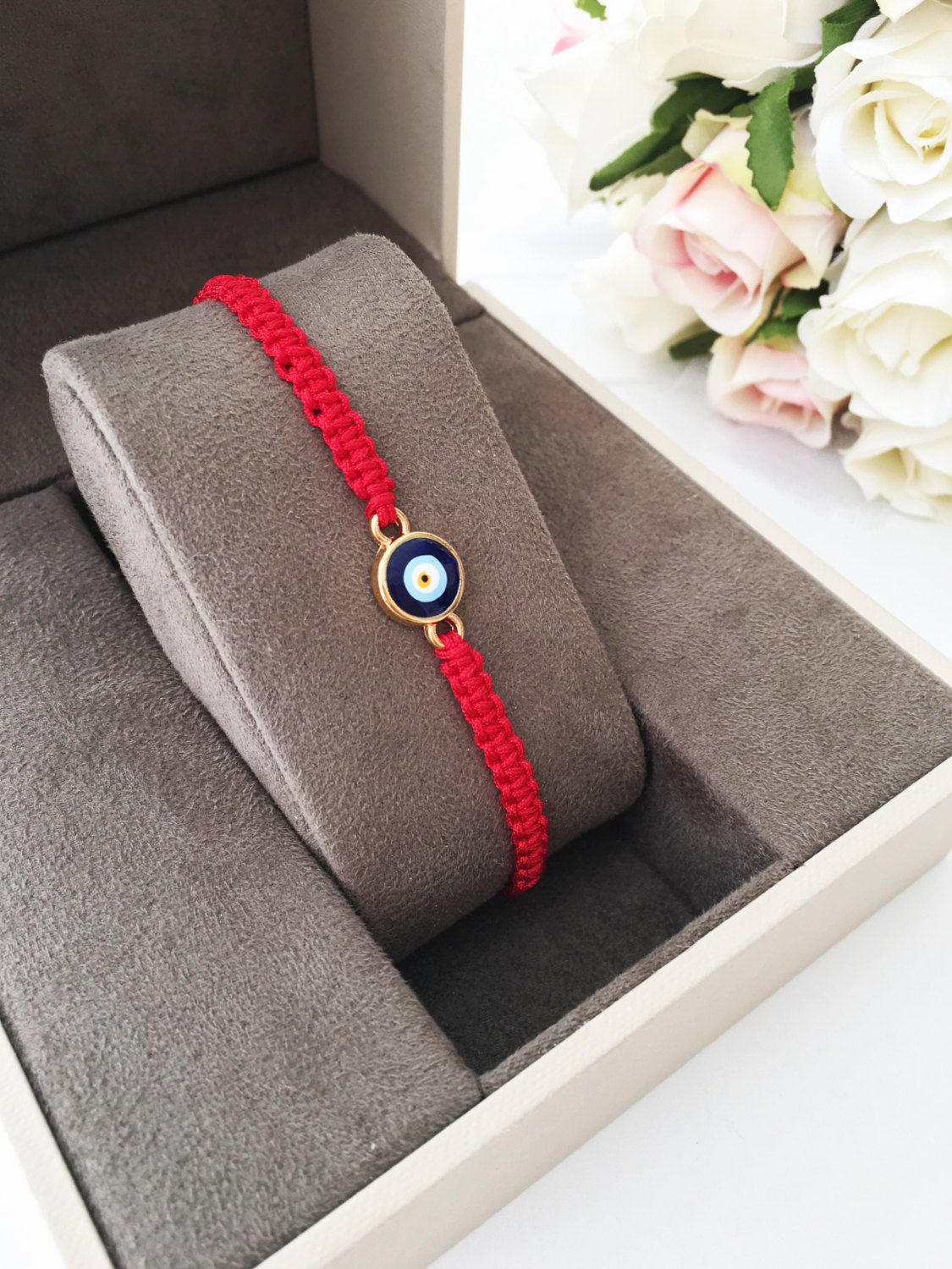 Handmade red string evil eye bracelet featuring a blue charm, adjustable for all wrist sizes.