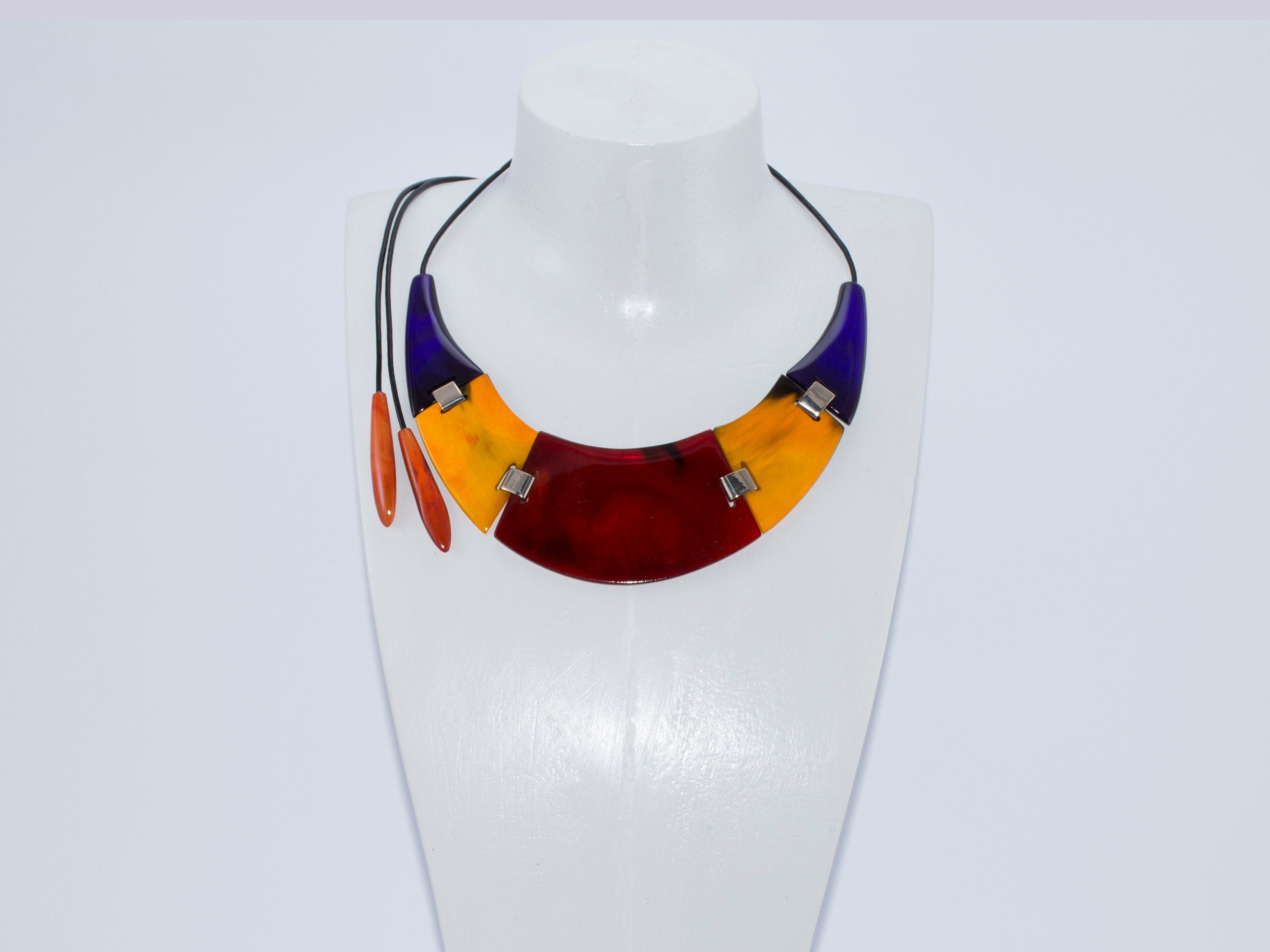 A vibrant red yellow necklace handmade from buffalo horn, featuring a unique crescent shape and adjustable length.