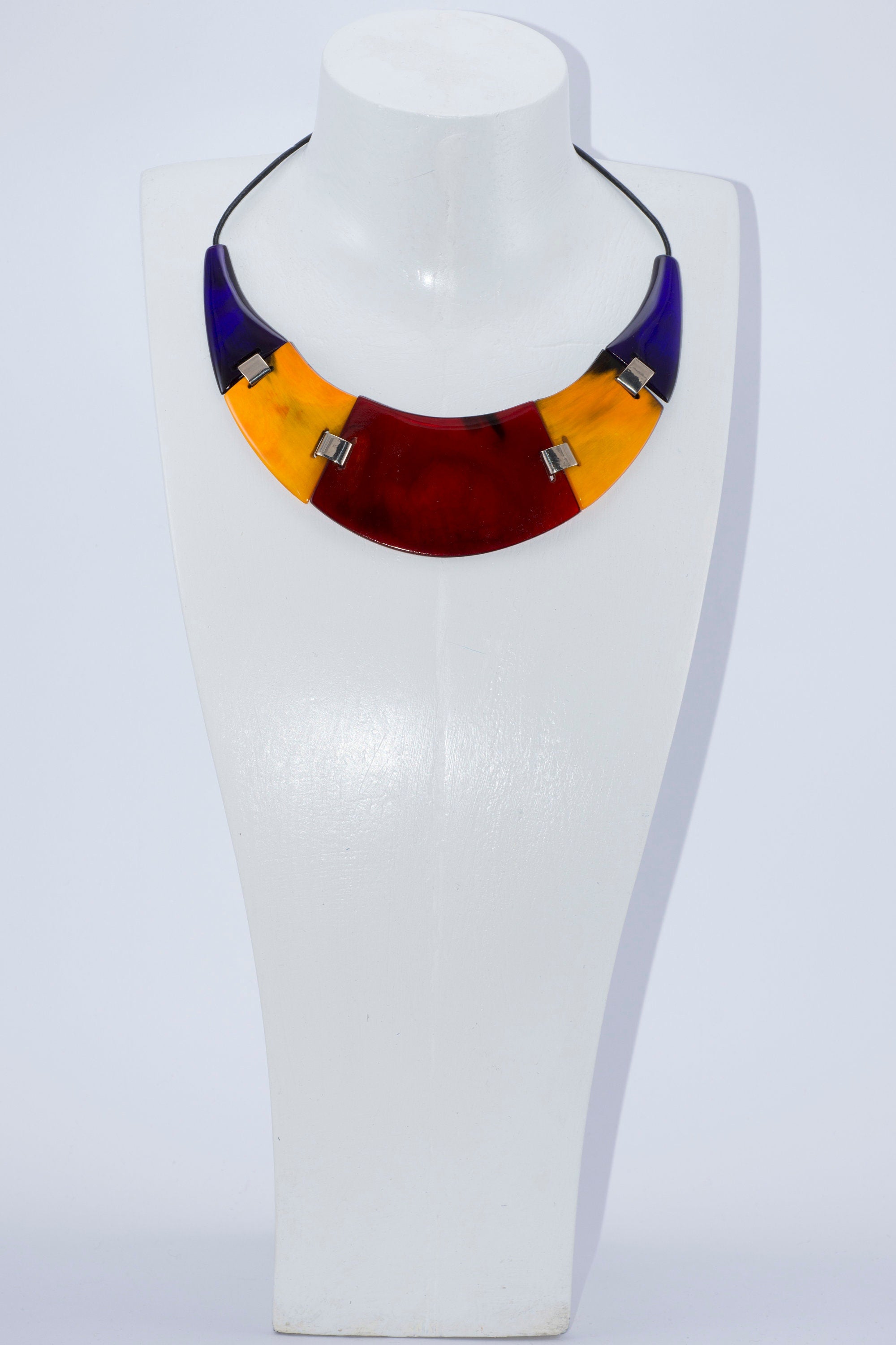 A vibrant red yellow necklace handmade from buffalo horn, featuring a unique crescent shape and adjustable length.