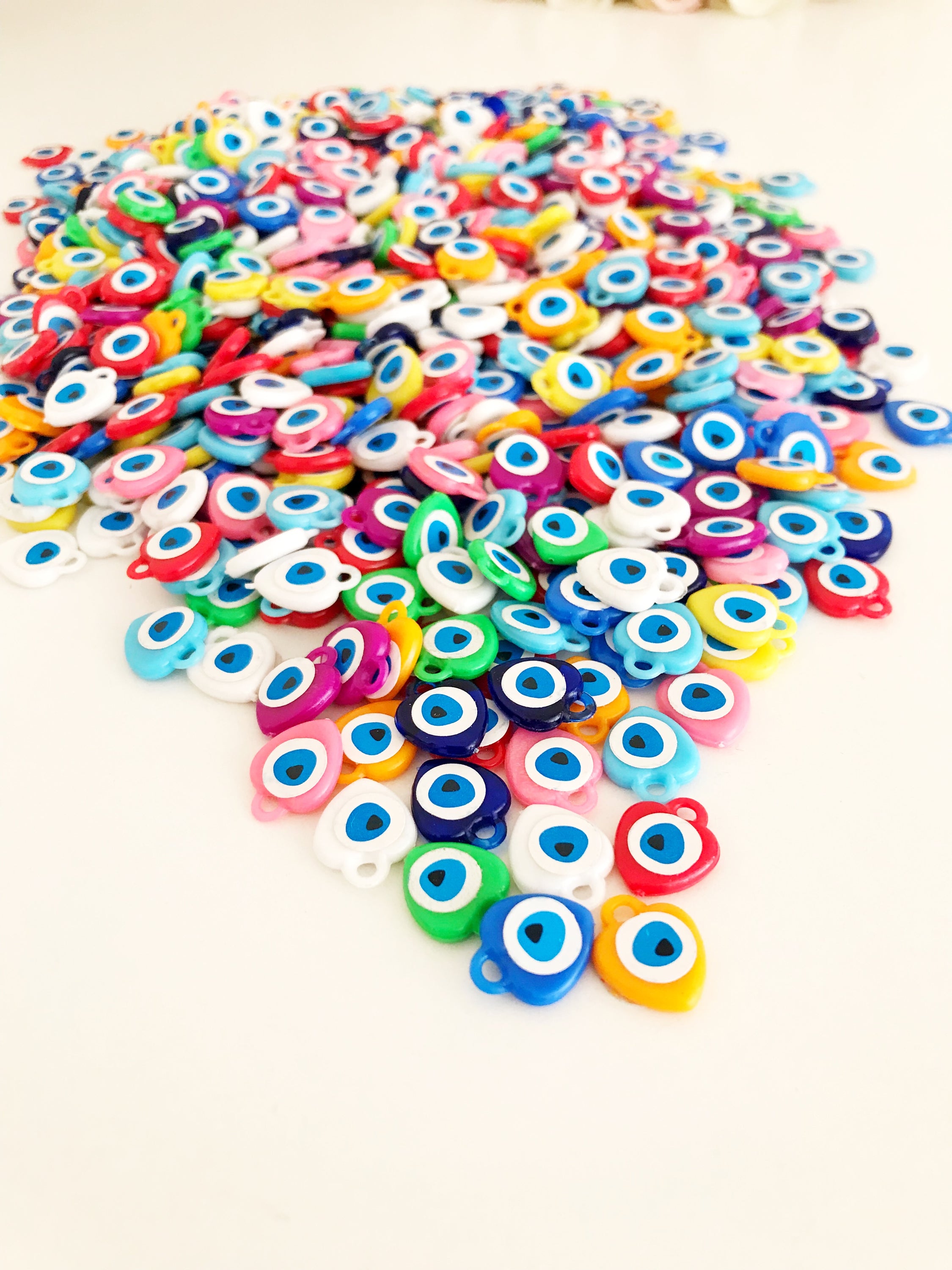 A collection of colorful resin evil eye beads in various shades, perfect for wedding favors, displayed on a white background.