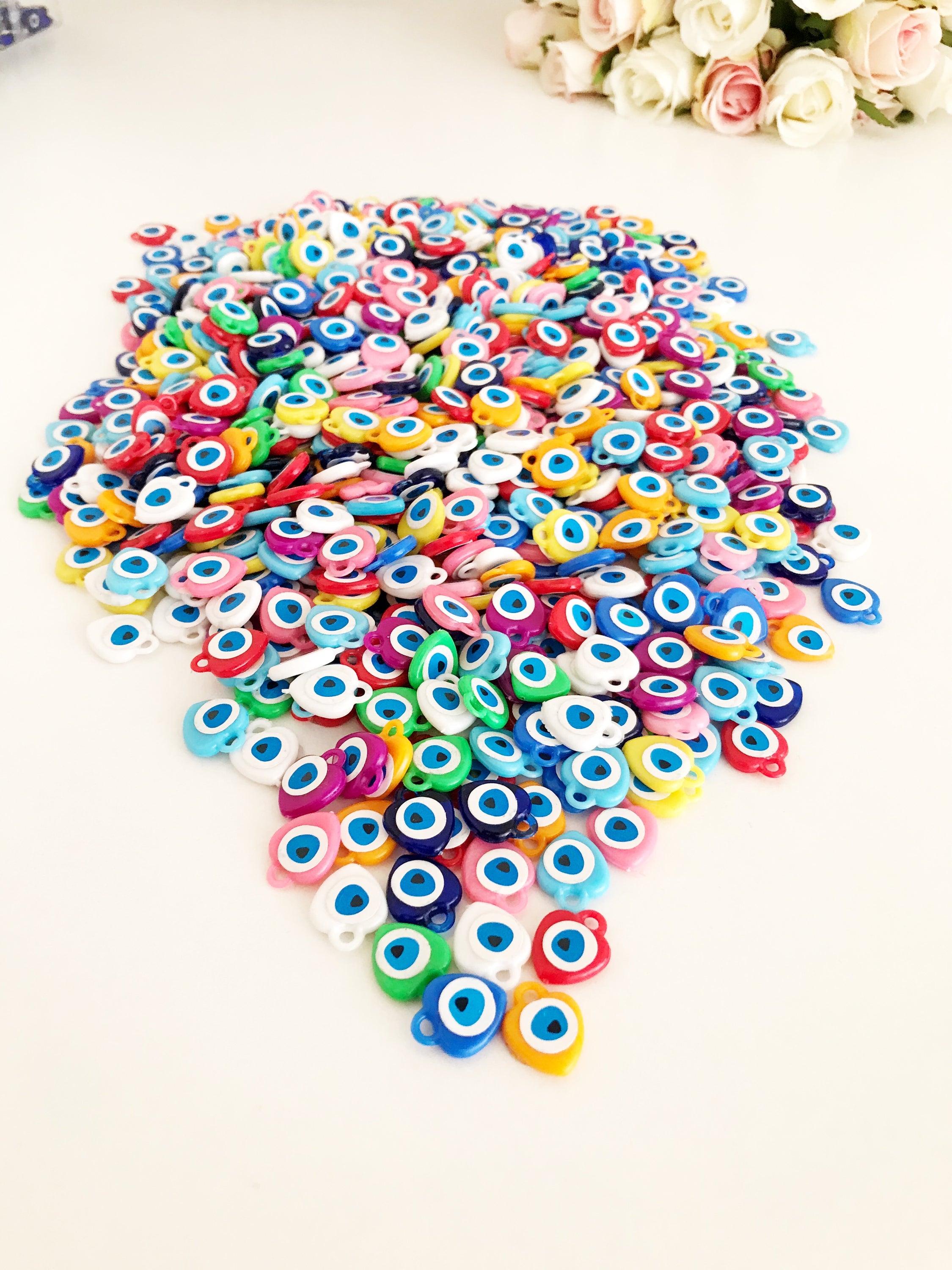 A collection of colorful resin evil eye beads in various shades, perfect for wedding favors, displayed on a white background.