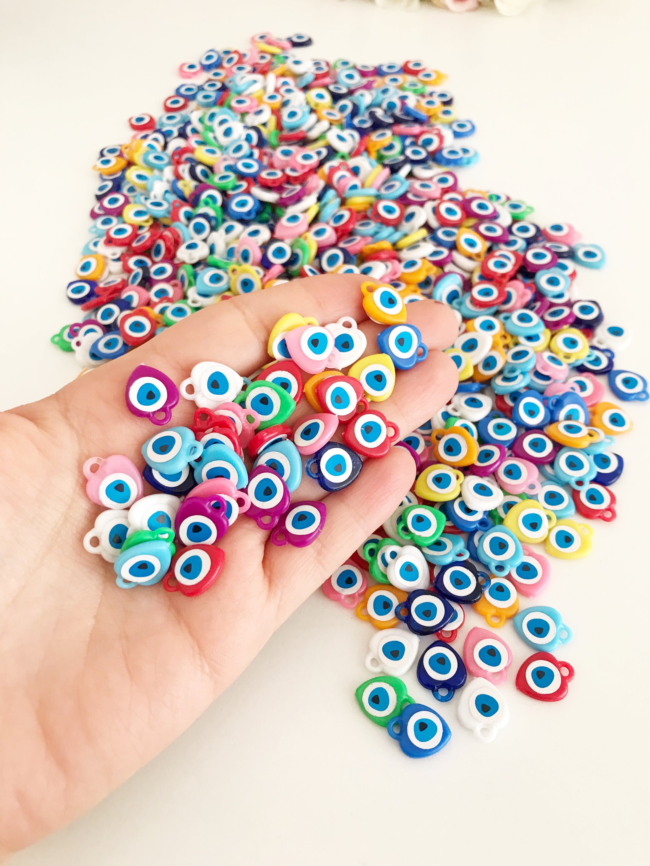 A collection of colorful resin evil eye beads in various shades, perfect for wedding favors, displayed on a white background.