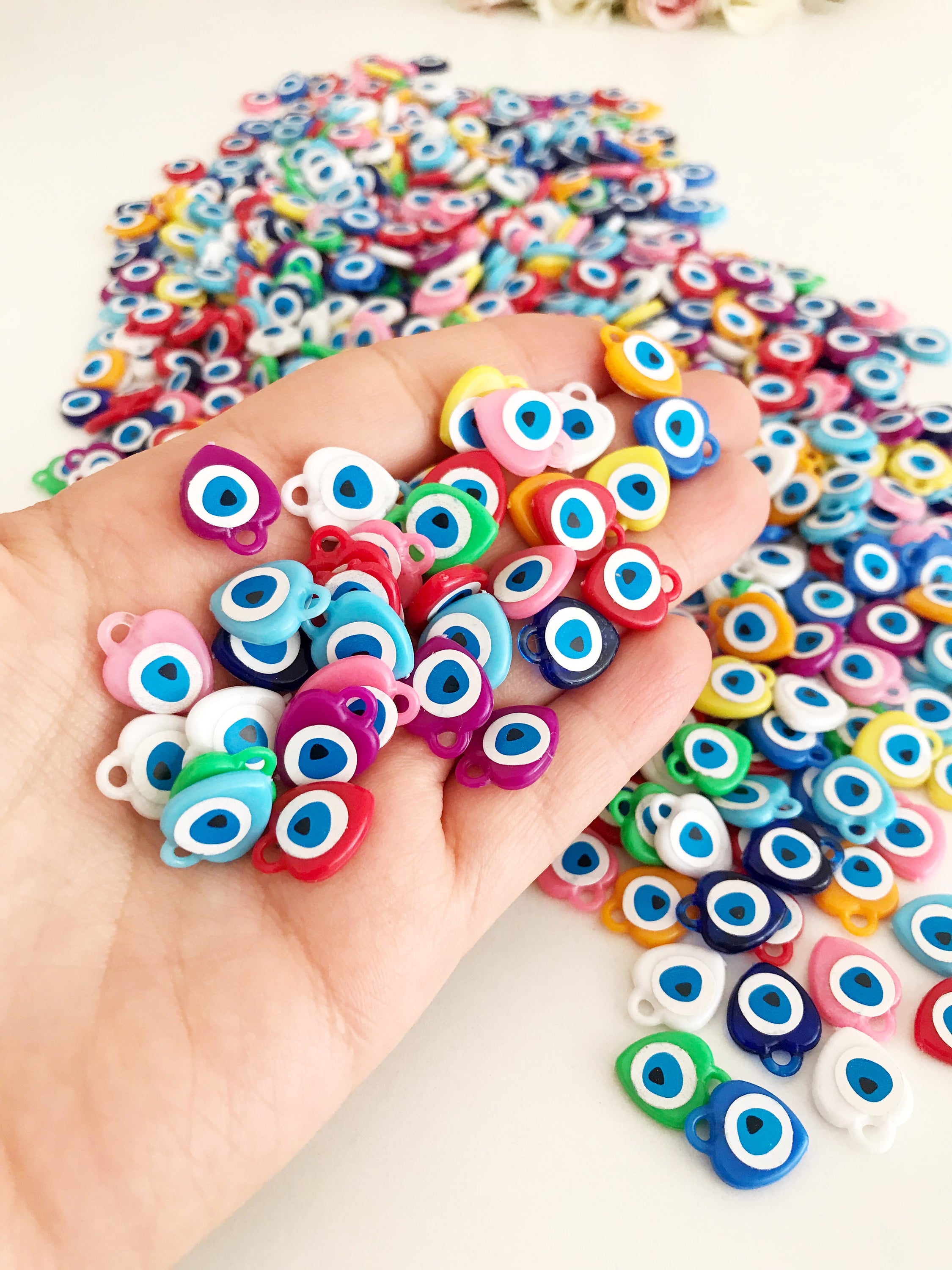 A collection of colorful resin evil eye beads in various shades, perfect for wedding favors, displayed on a white background.