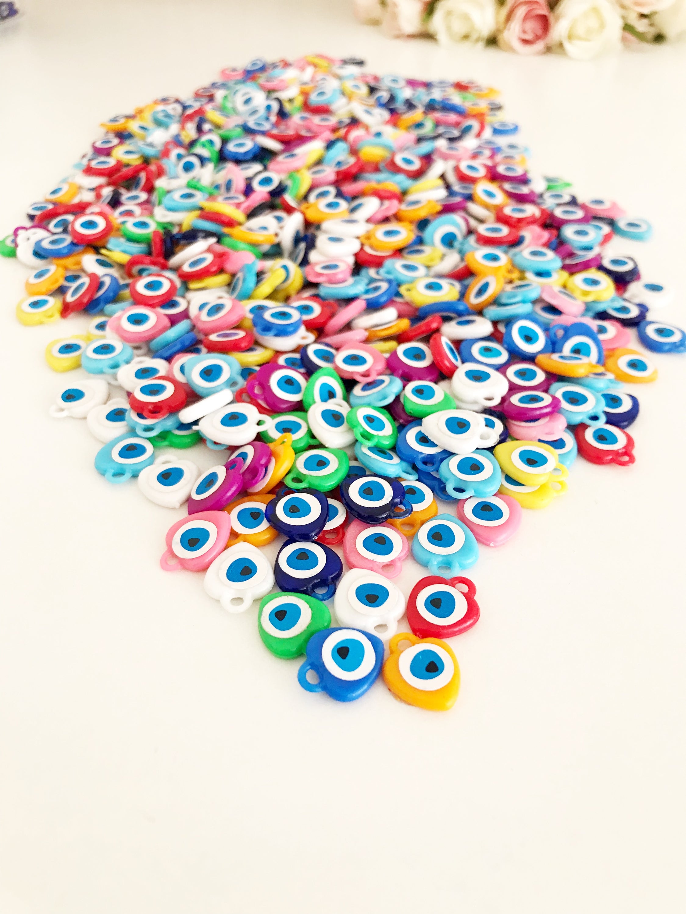 A collection of colorful resin evil eye beads in various shades, perfect for wedding favors, displayed on a white background.