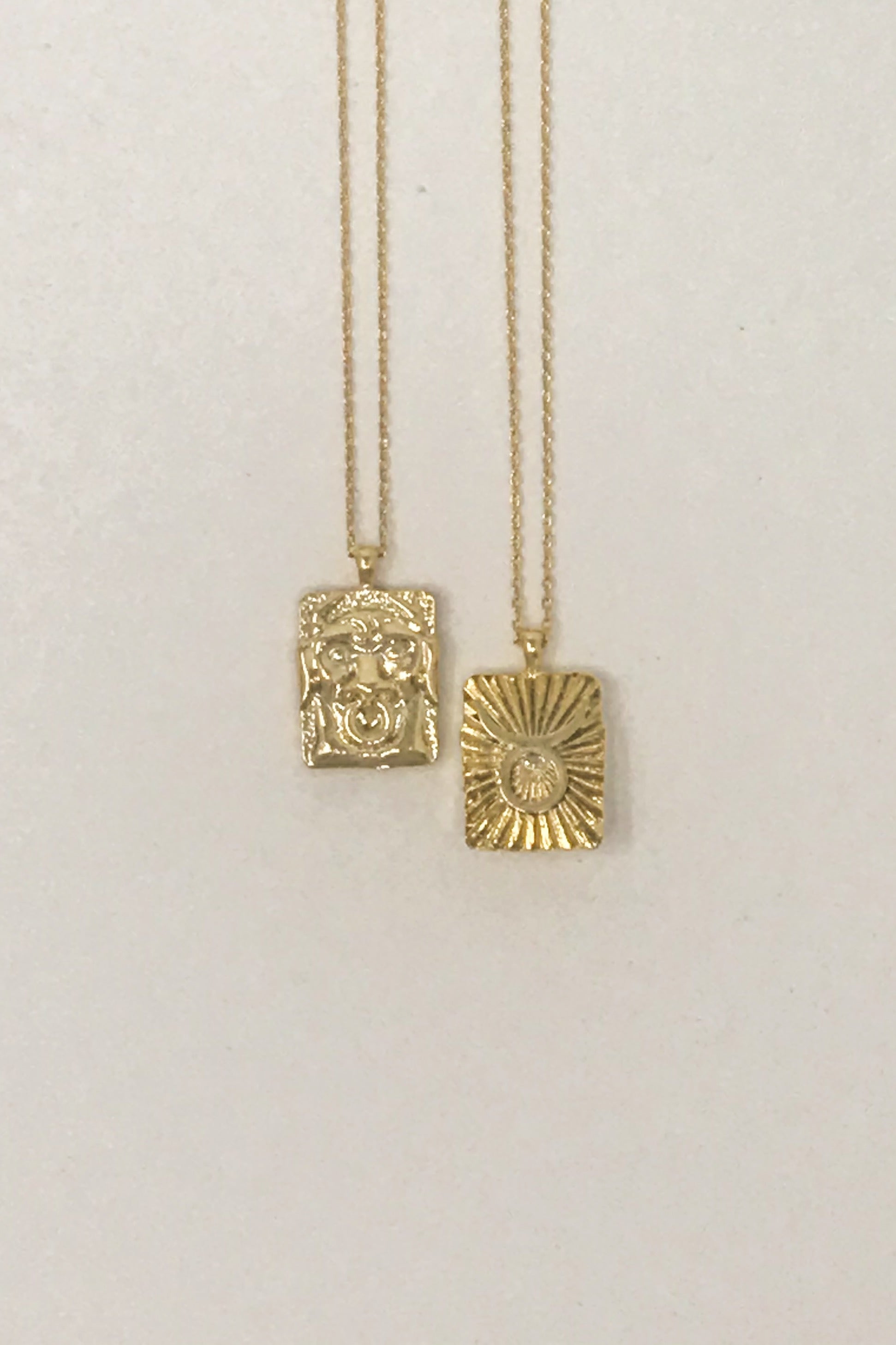 Elegant reversible gold pendant necklace featuring zodiac constellation signs, showcasing both sides of the design.