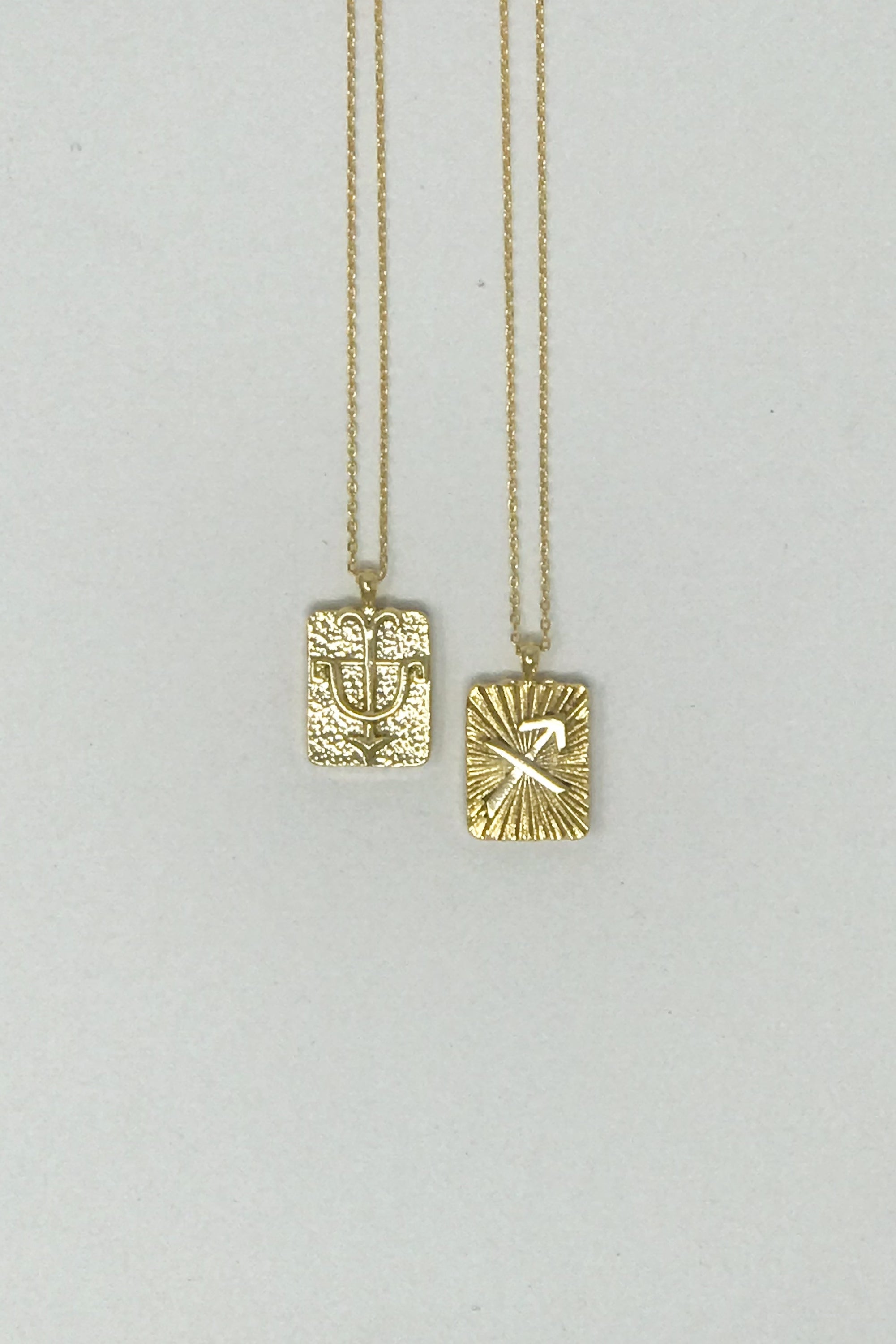 Elegant reversible gold pendant necklace featuring zodiac constellation signs, showcasing both sides of the design.