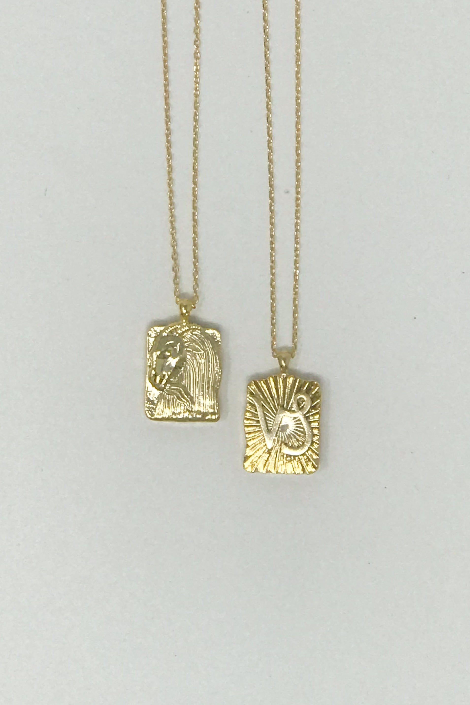 Elegant reversible gold pendant necklace featuring zodiac constellation signs, showcasing both sides of the design.