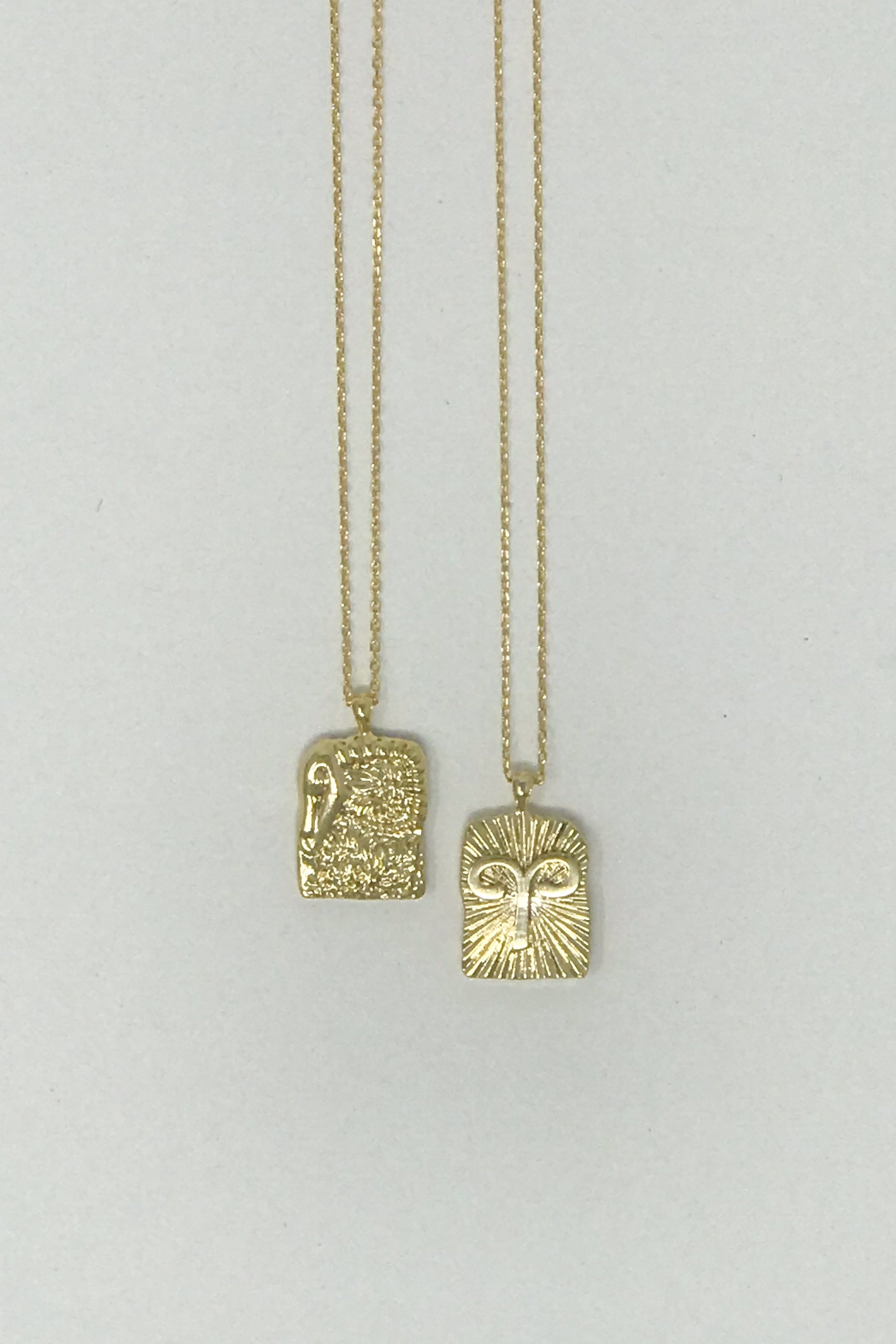 Elegant reversible gold pendant necklace featuring zodiac constellation signs, showcasing both sides of the design.