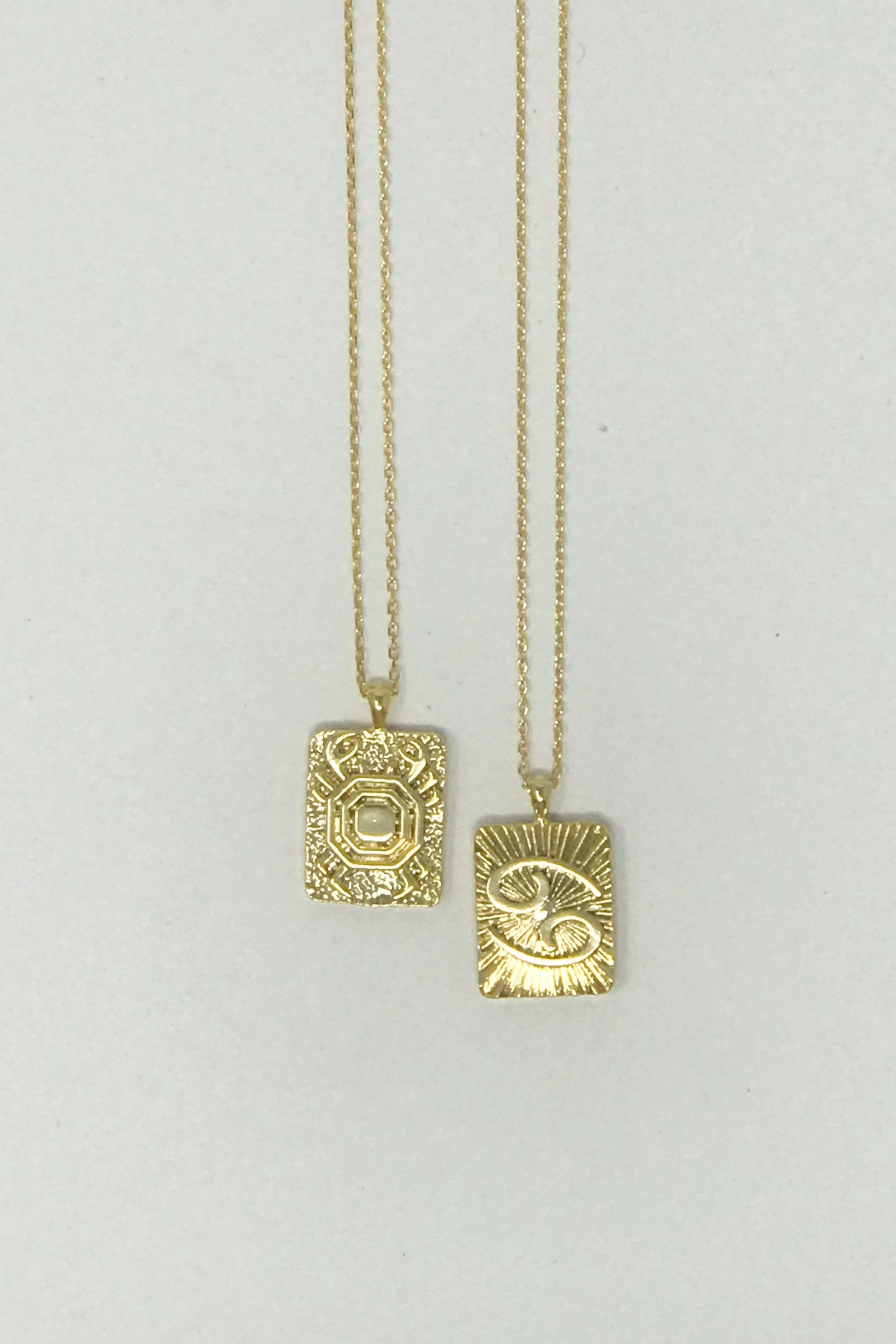 Elegant reversible gold pendant necklace featuring zodiac constellation signs, showcasing both sides of the design.