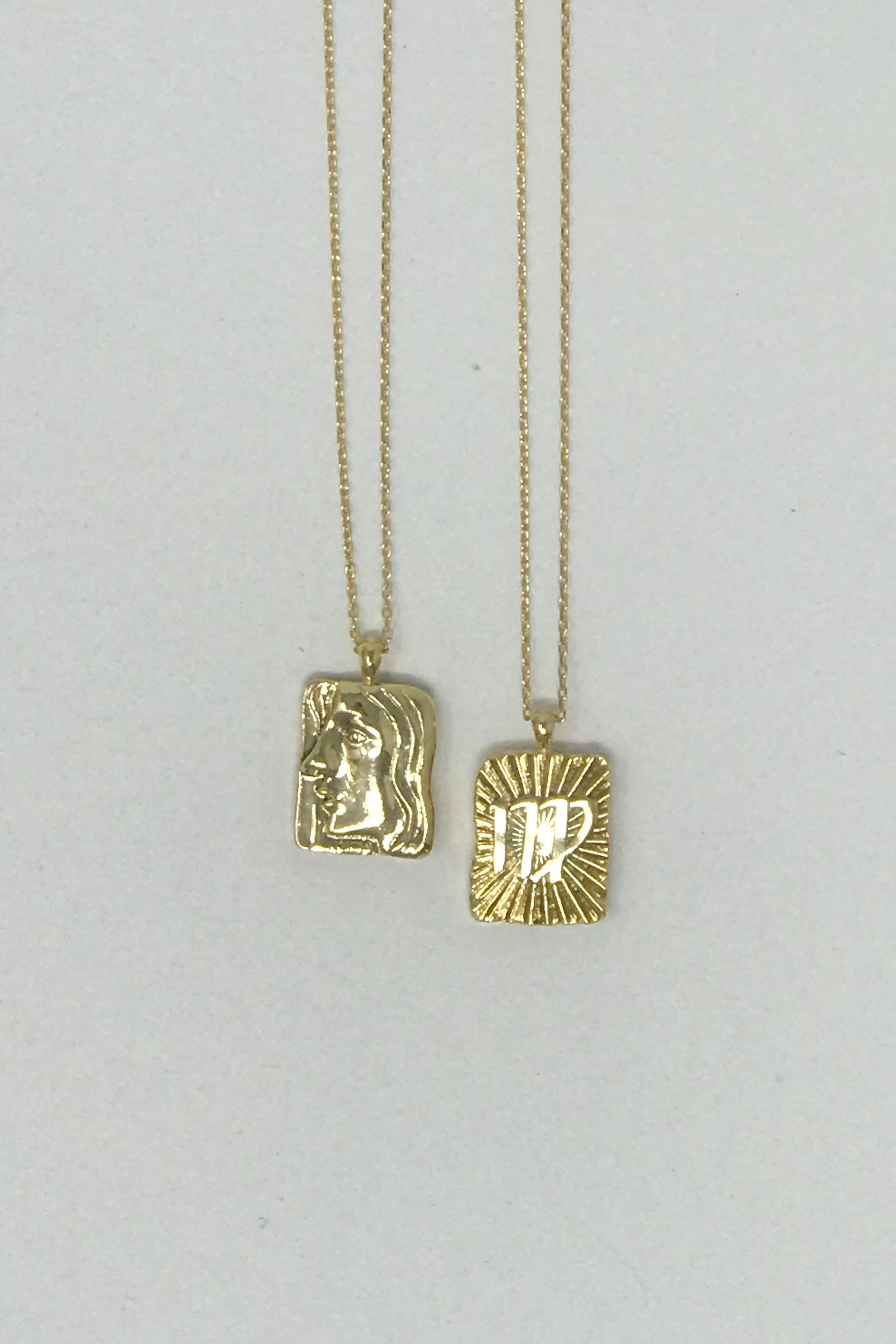 Elegant reversible gold pendant necklace featuring zodiac constellation signs, showcasing both sides of the design.