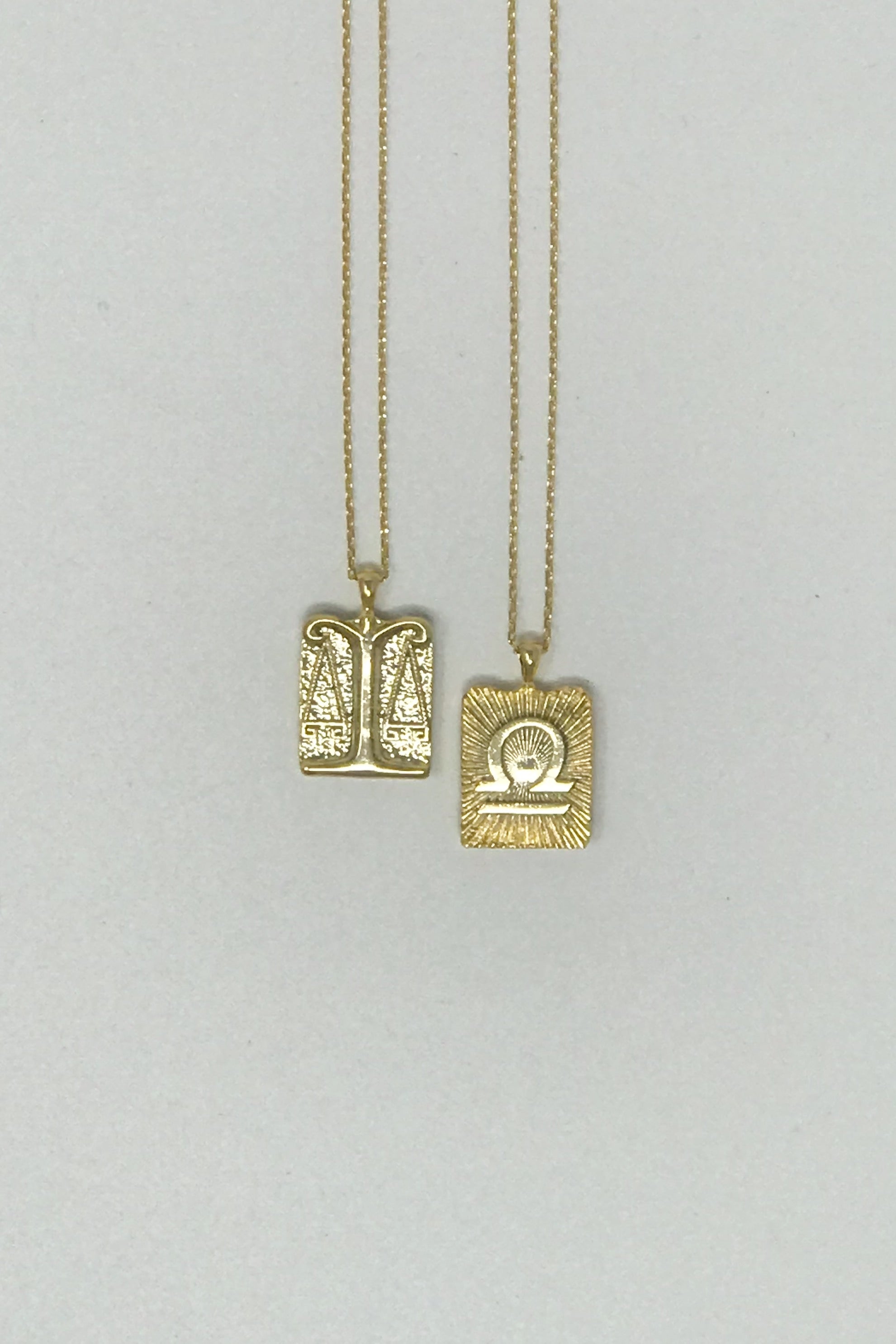 Elegant reversible gold pendant necklace featuring zodiac constellation signs, showcasing both sides of the design.