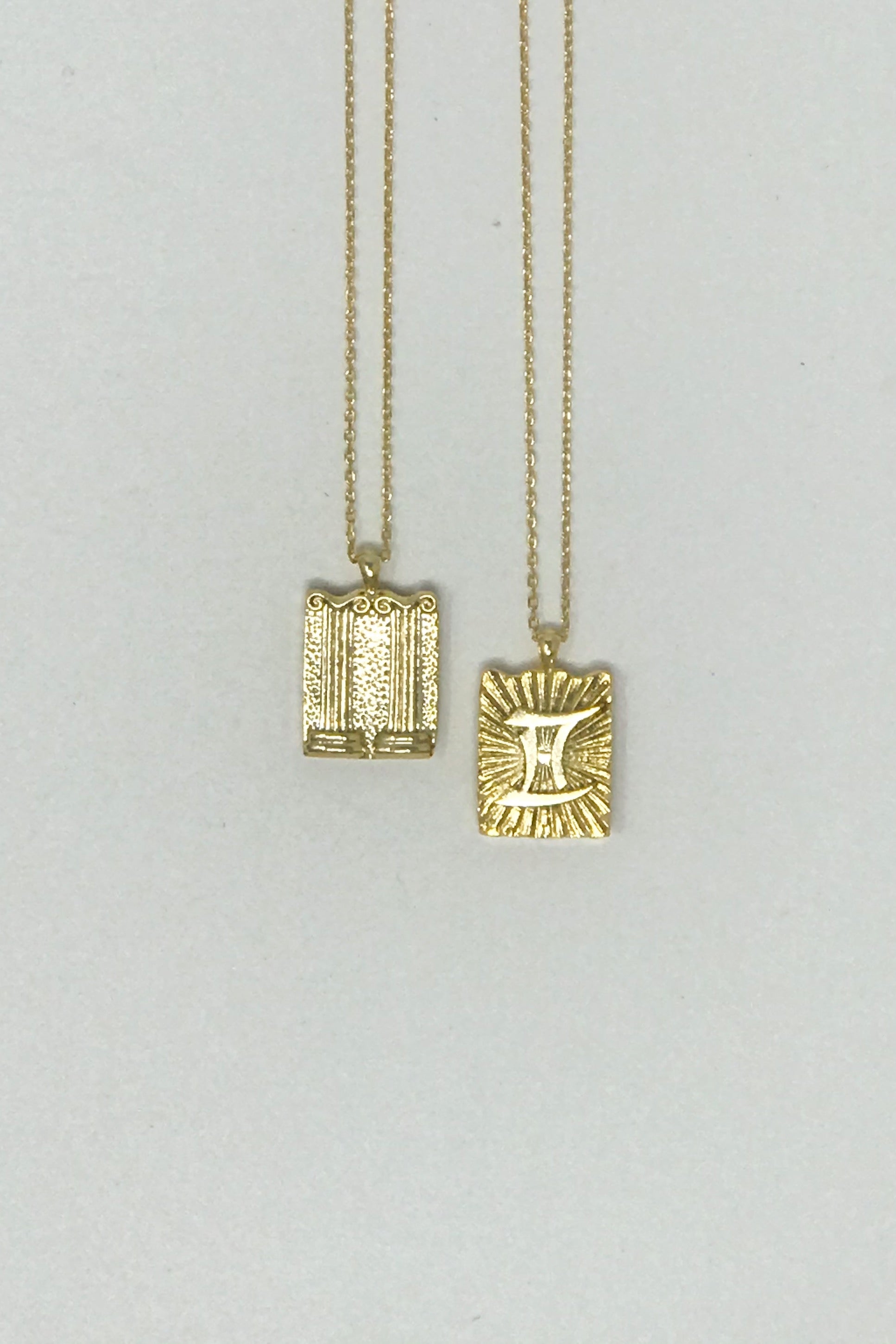 Elegant reversible gold pendant necklace featuring zodiac constellation signs, showcasing both sides of the design.