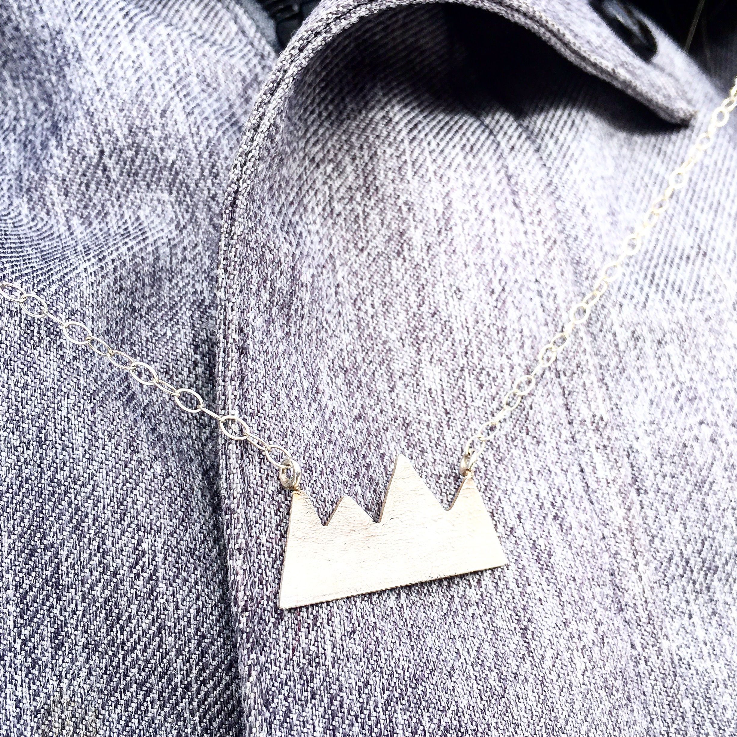 Rocky Mountains Necklace featuring a hand-cut mountain range design in reticulated silver, hanging on a sterling silver chain.