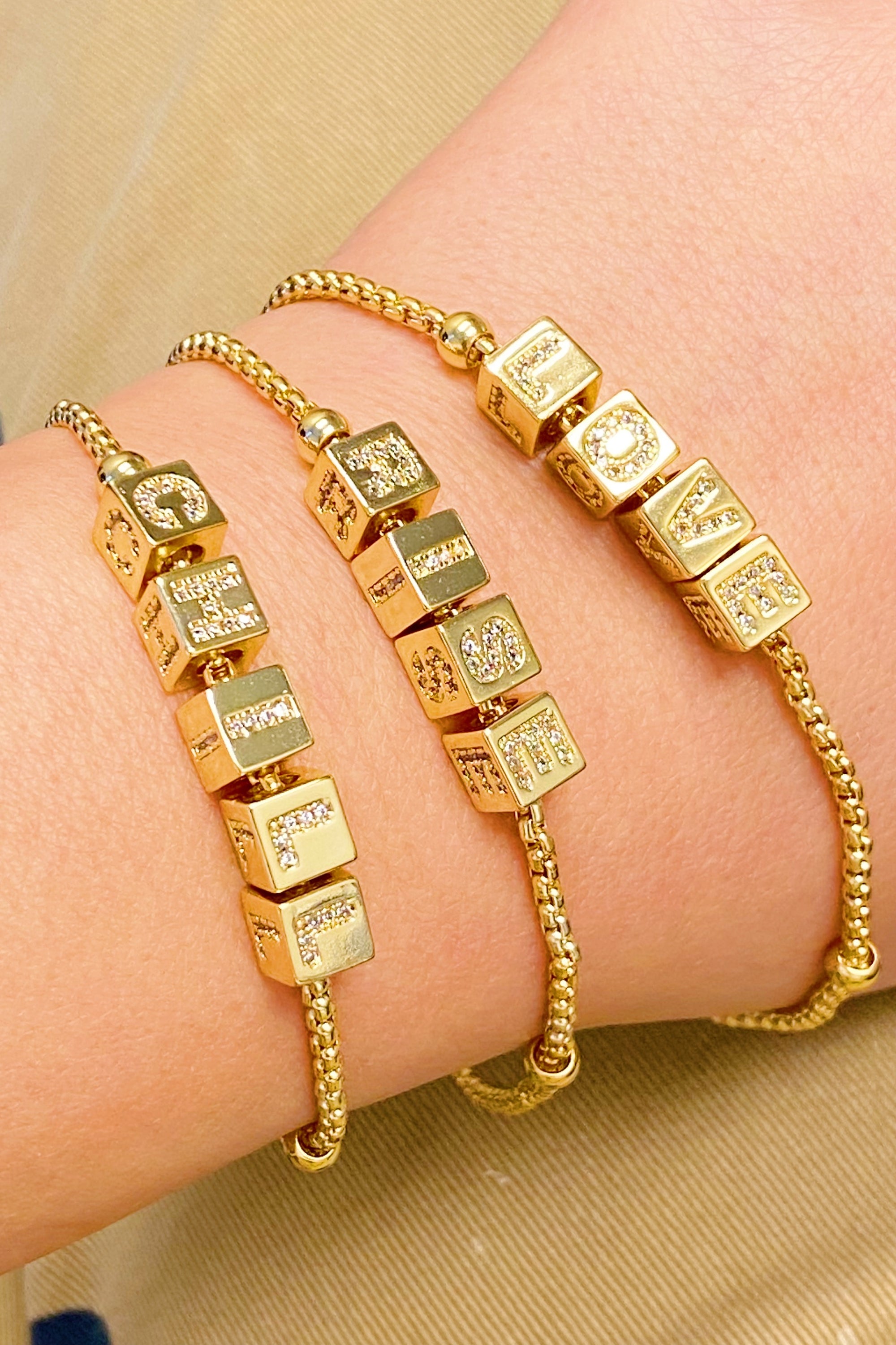 Gold plated charm bracelet featuring rolling dice with shiny paved letters and adjustable sliding chain.