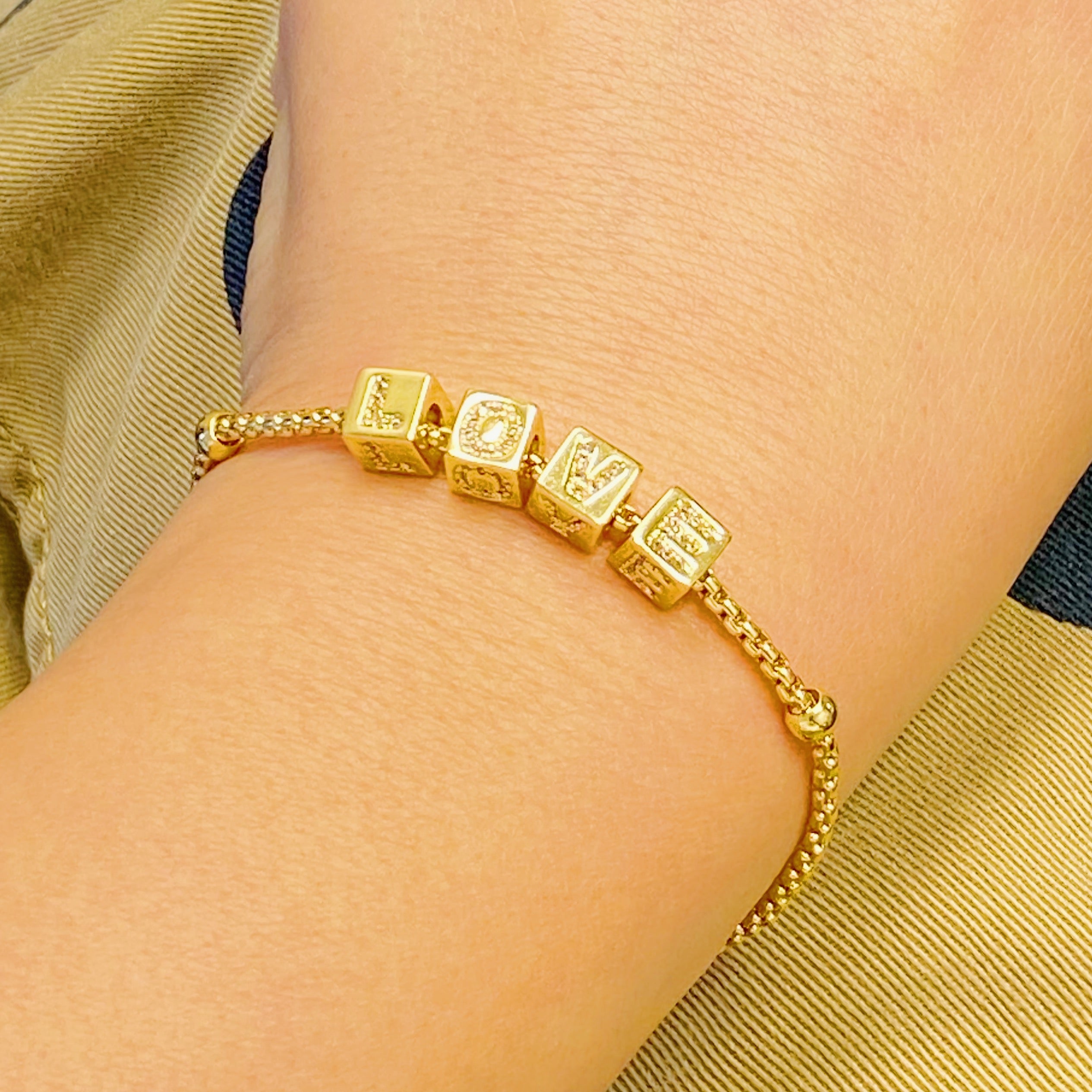 Gold plated charm bracelet featuring rolling dice with shiny paved letters and adjustable sliding chain.