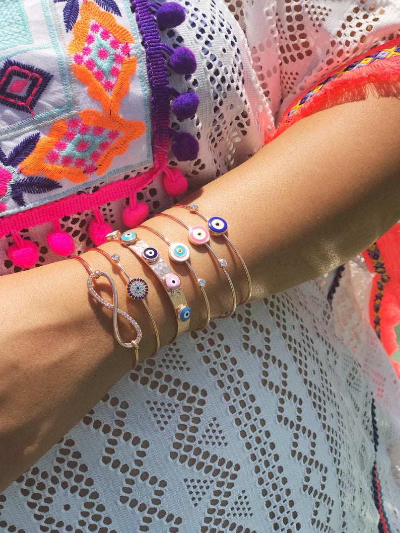 A beautiful rose gold bangle bracelet featuring a movable blue evil eye charm, showcasing its elegant design and adjustable fit.