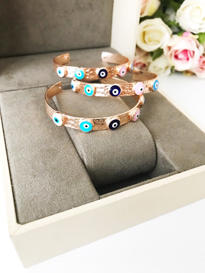 Elegant rose gold bangle bracelet featuring a movable evil eye charm, crafted from tarnish-resistant stainless steel.