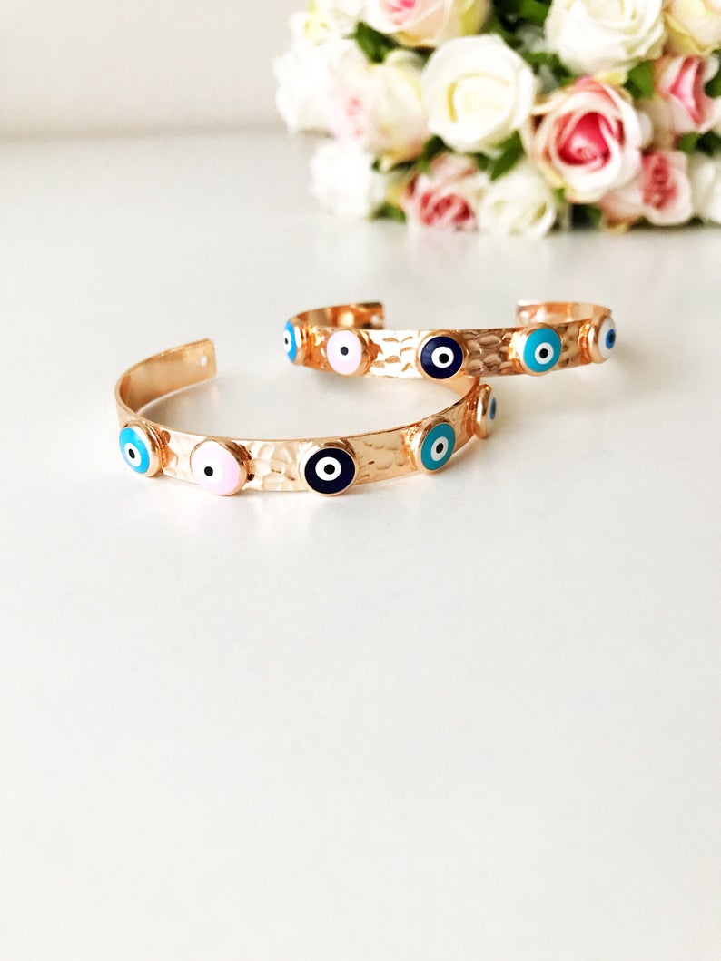 Elegant rose gold bangle bracelet featuring a movable evil eye charm, crafted from tarnish-resistant stainless steel.