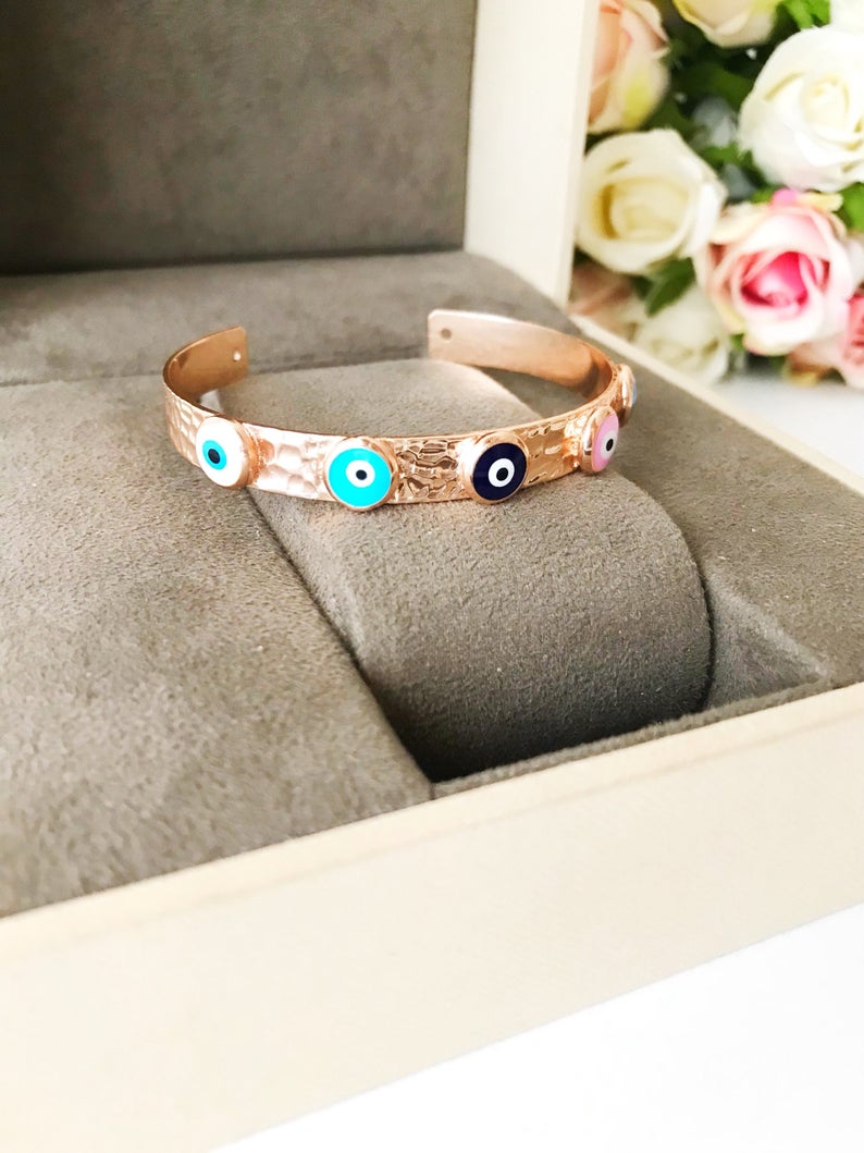 Elegant rose gold bangle bracelet featuring a movable evil eye charm, crafted from tarnish-resistant stainless steel.