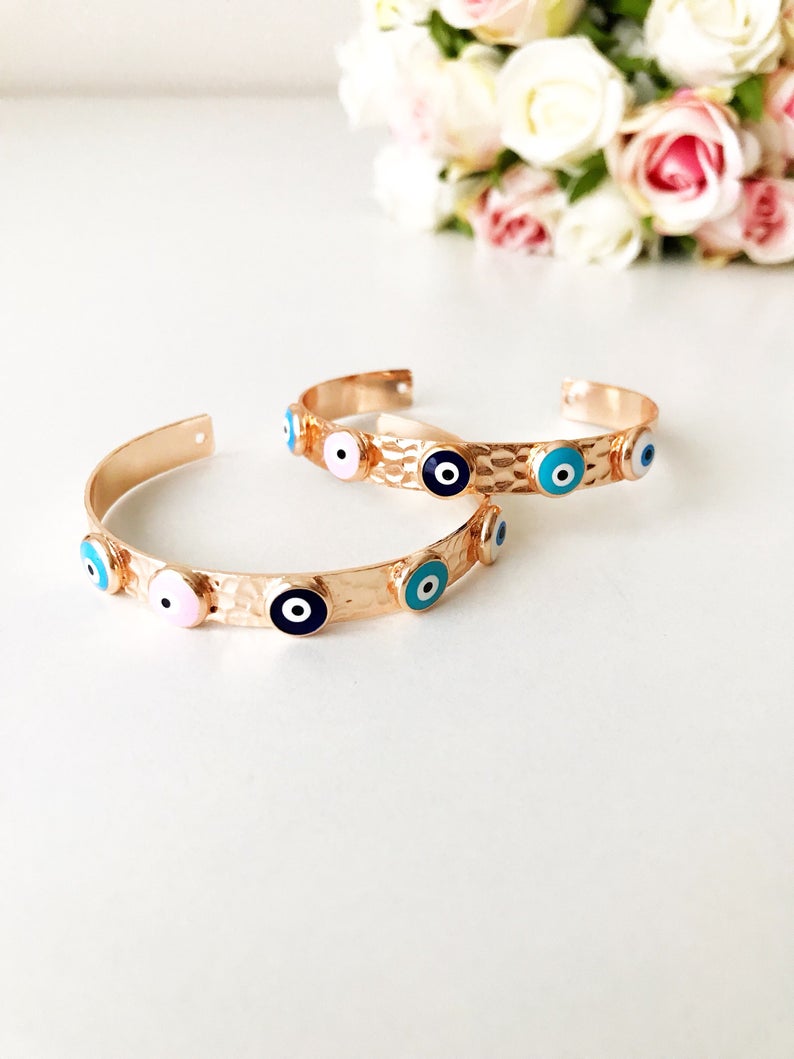 Elegant rose gold bangle bracelet featuring a movable evil eye charm, crafted from tarnish-resistant stainless steel.