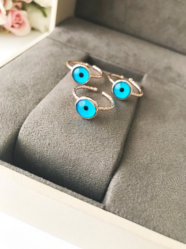 A beautiful rose gold adjustable ring featuring a blue evil eye bead, symbolizing protection and elegance.