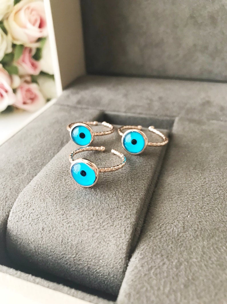 A beautiful rose gold adjustable ring featuring a blue evil eye bead, symbolizing protection and elegance.