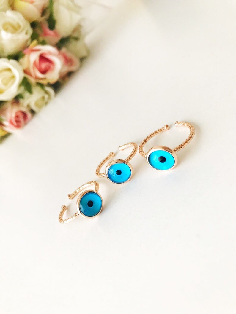 A beautiful rose gold adjustable ring featuring a blue evil eye bead, symbolizing protection and elegance.