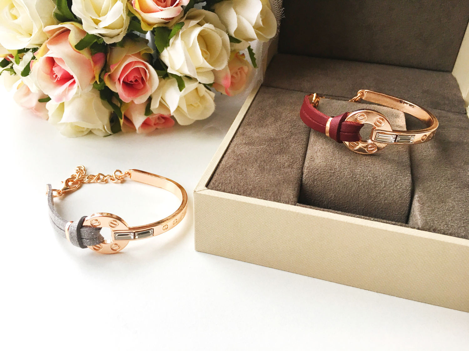 A stylish rose gold leather bracelet featuring a cubic zirconia charm, available in red and gray colors, showcasing its adjustable design.