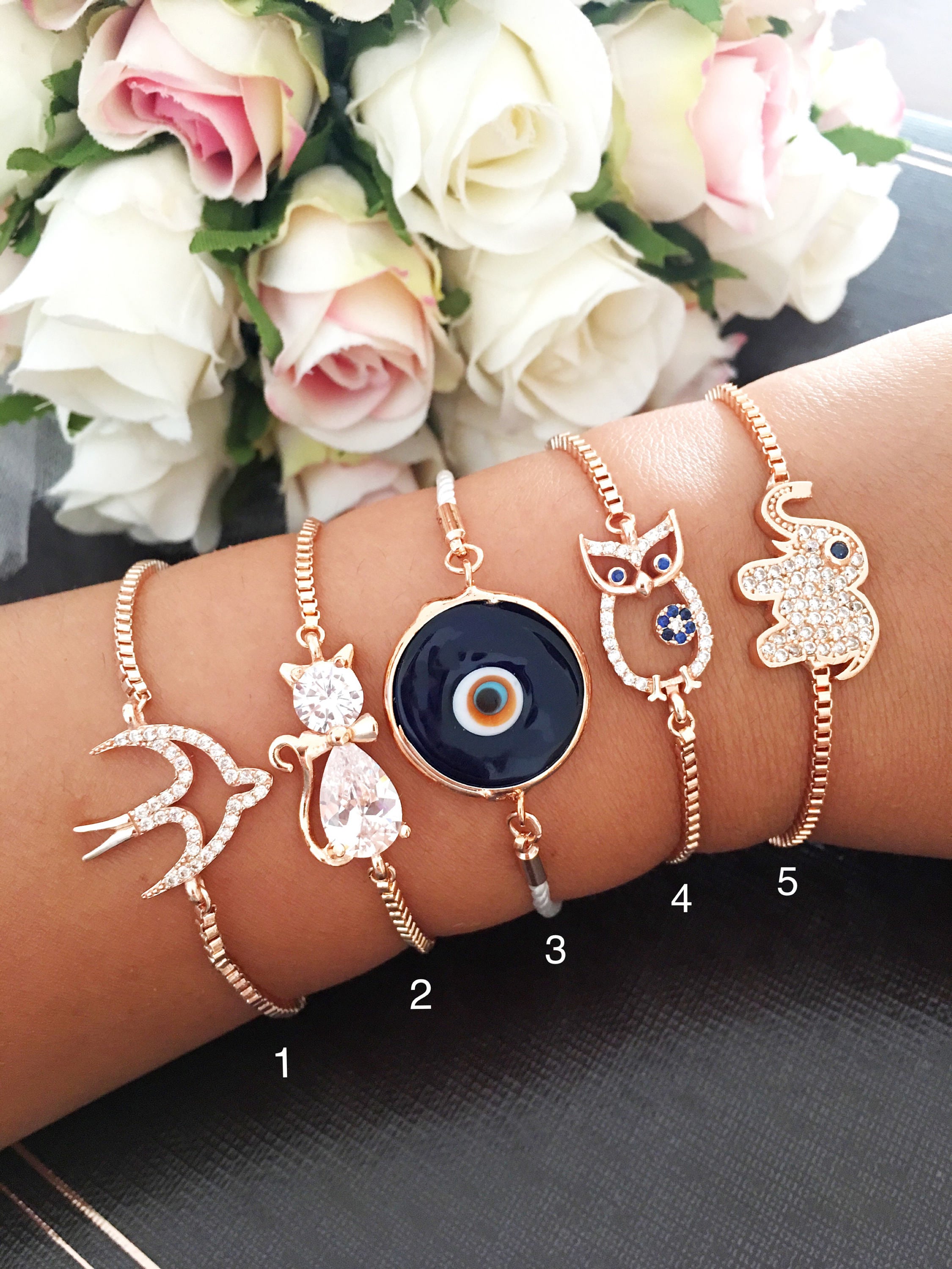 A beautiful rose gold bracelet featuring a Murano evil eye charm and various animal designs, showcasing its handmade craftsmanship.