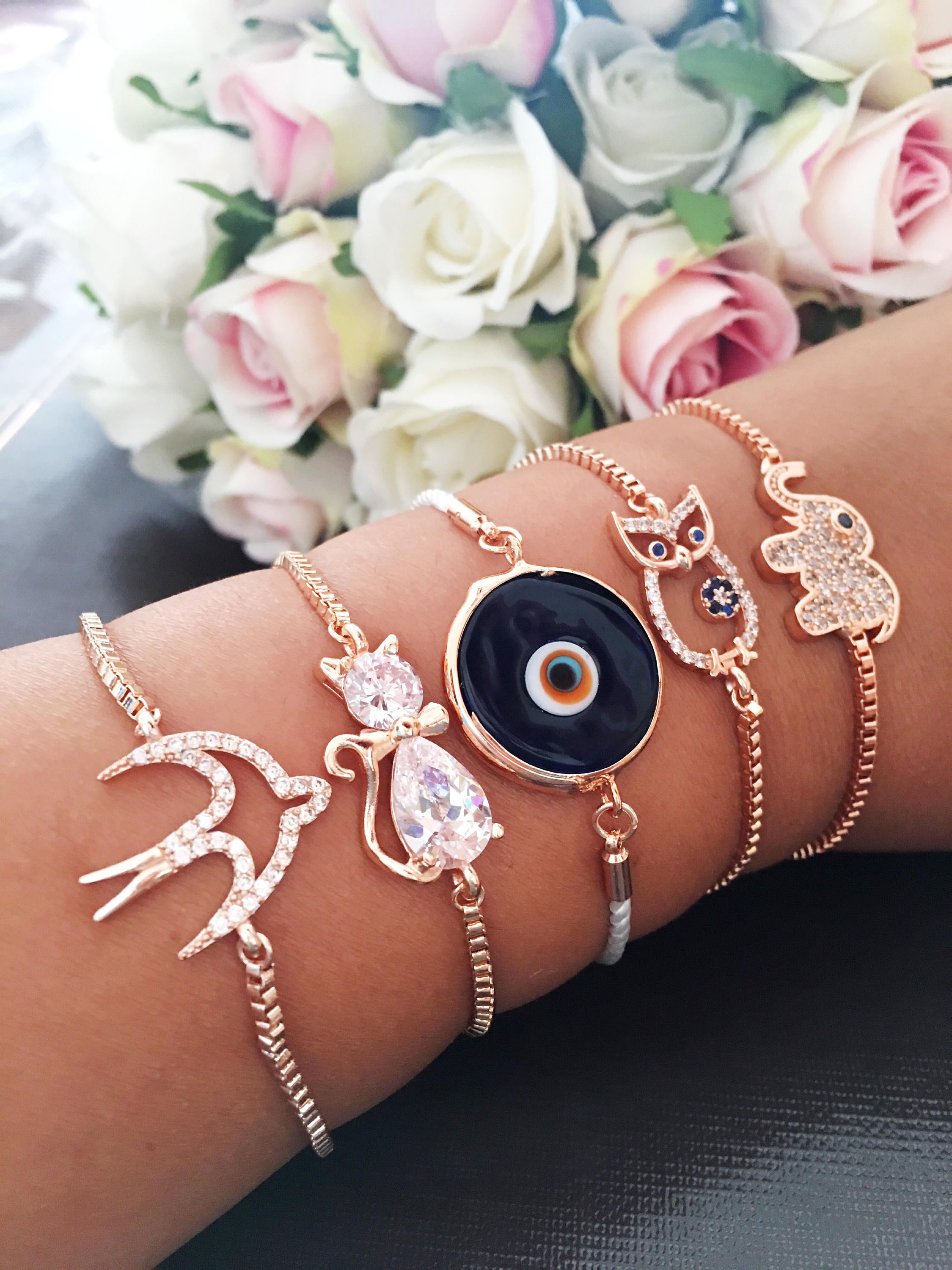 A beautiful rose gold bracelet featuring a Murano evil eye charm and various animal designs, showcasing its handmade craftsmanship.